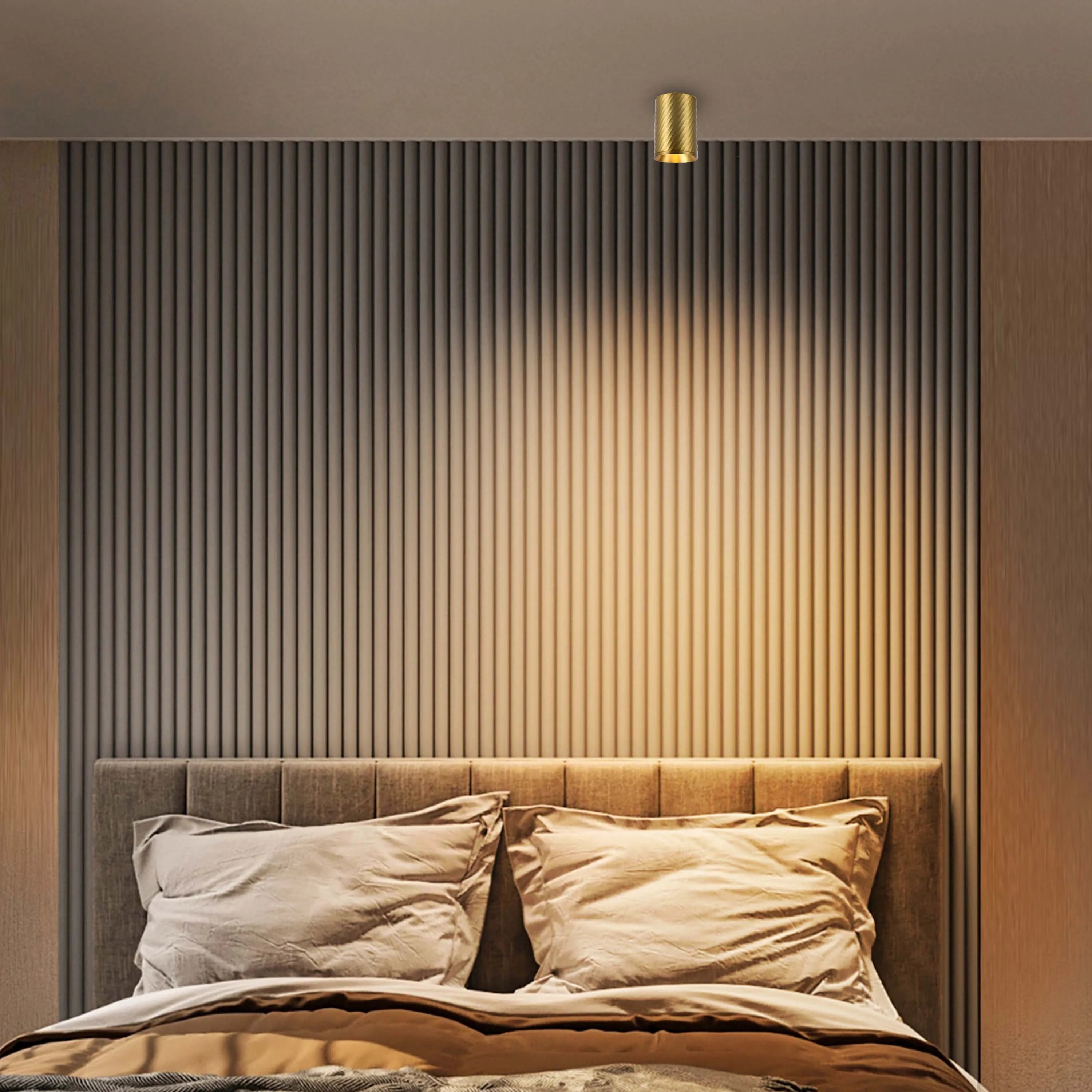 Warm light shines from a cylindrical ceiling light, illuminating a bedroom with a stylish bed and textured wall.