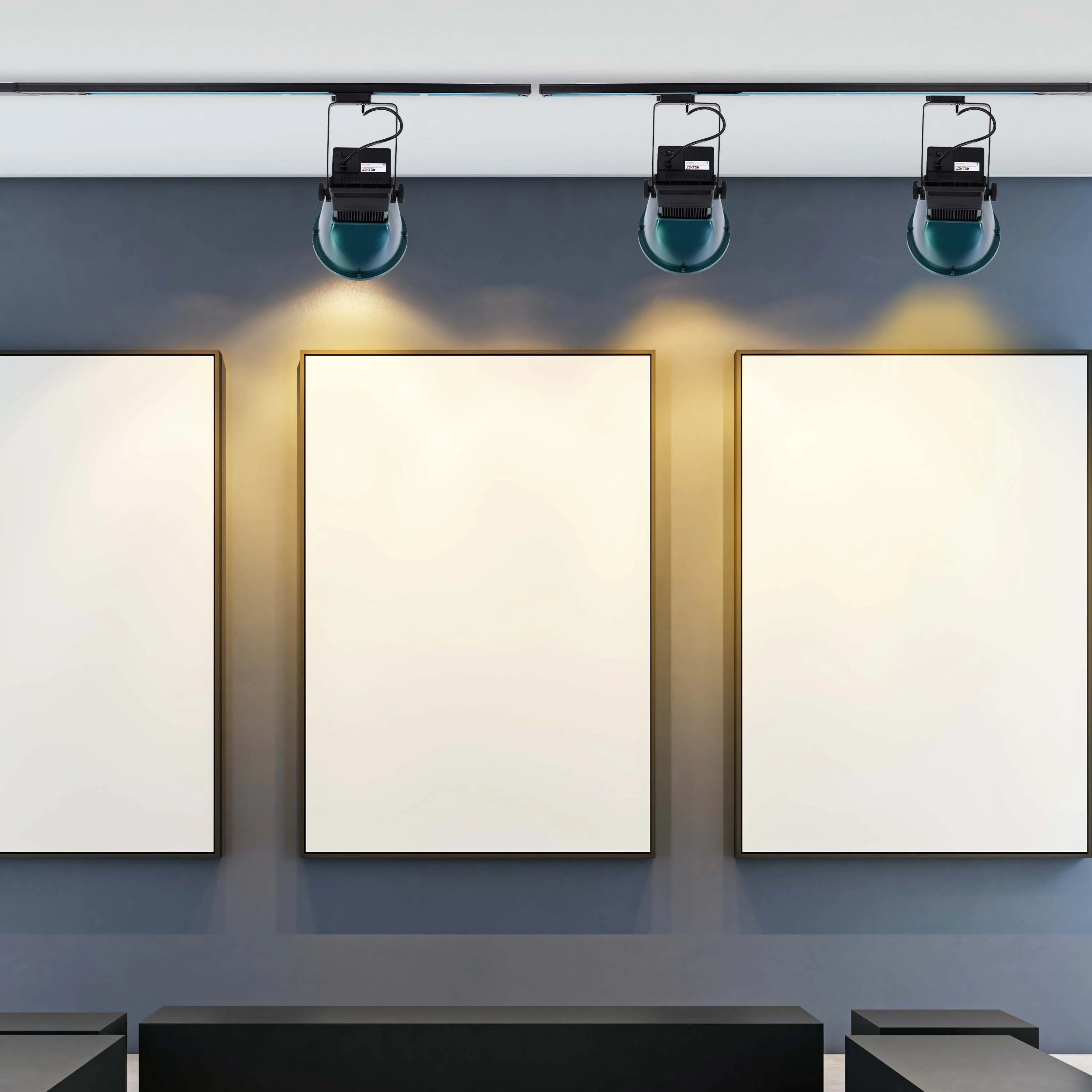 Gallery track lighting illuminates three framed artworks, highlighting the gallery’s exhibition. Perfect for art lighting solutions.