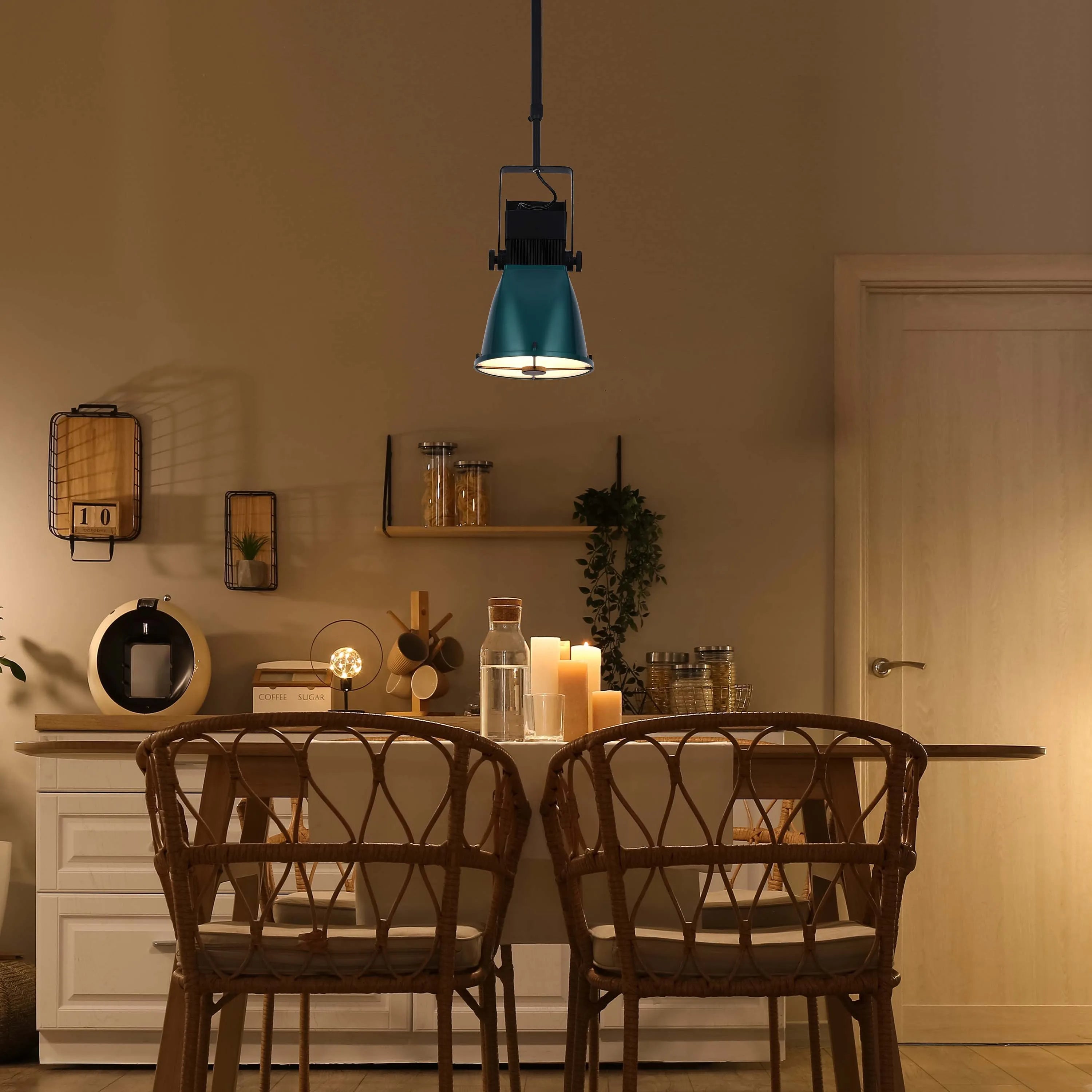 An adjustable teal pendant light illuminates a dining area, casting a warm glow on the tabletop and wicker chairs below.