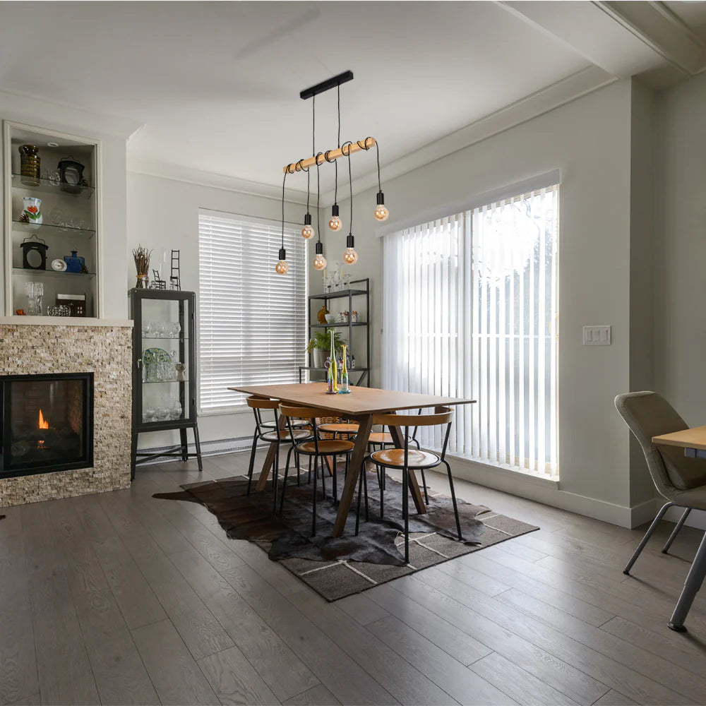 Statement pendant light with six Edison-style bulbs, hanging over a rustic dining table.