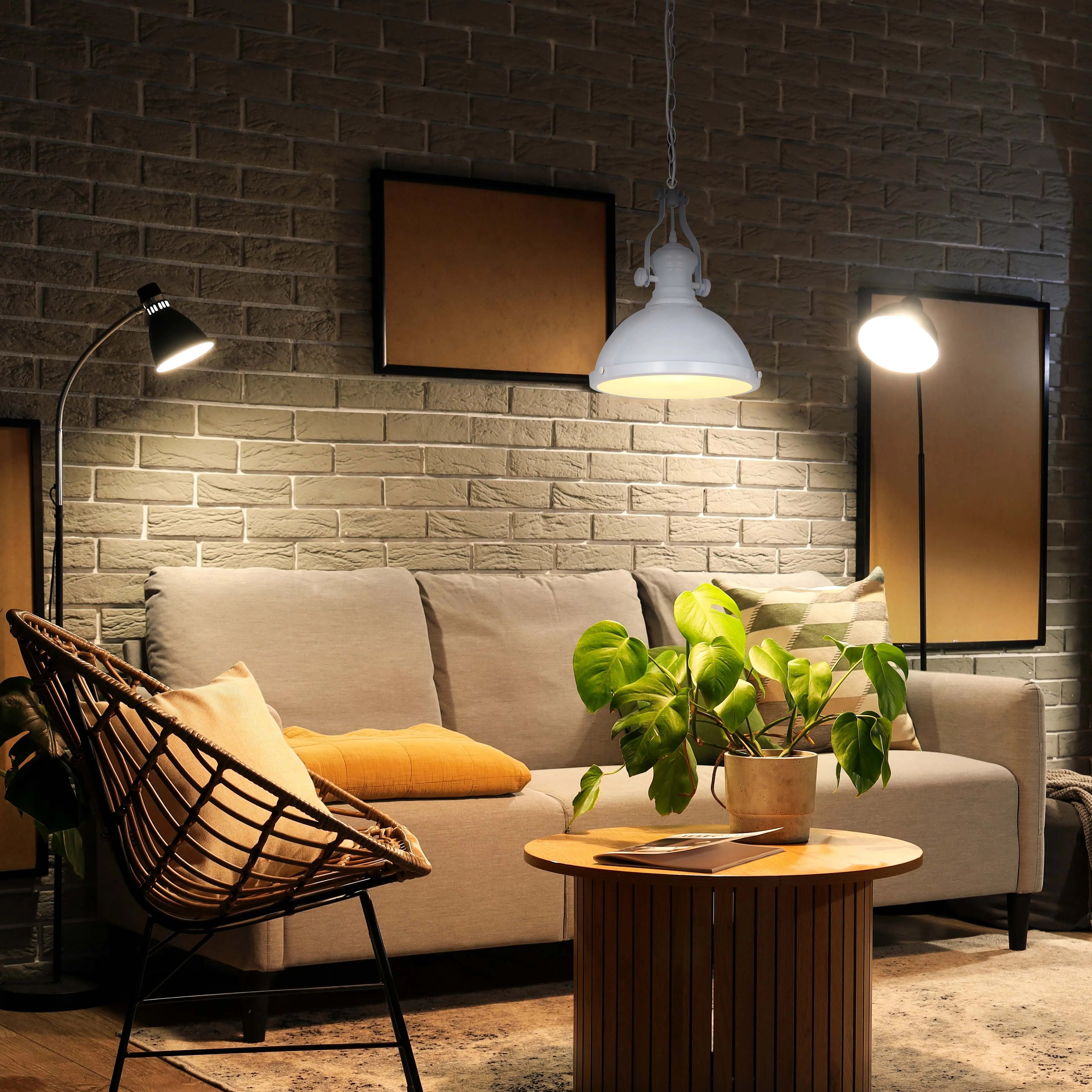 Cosy living room scene, lit by a pendant, wall and floor lamps. Warm lighting creates an inviting, atmospheric ambience.