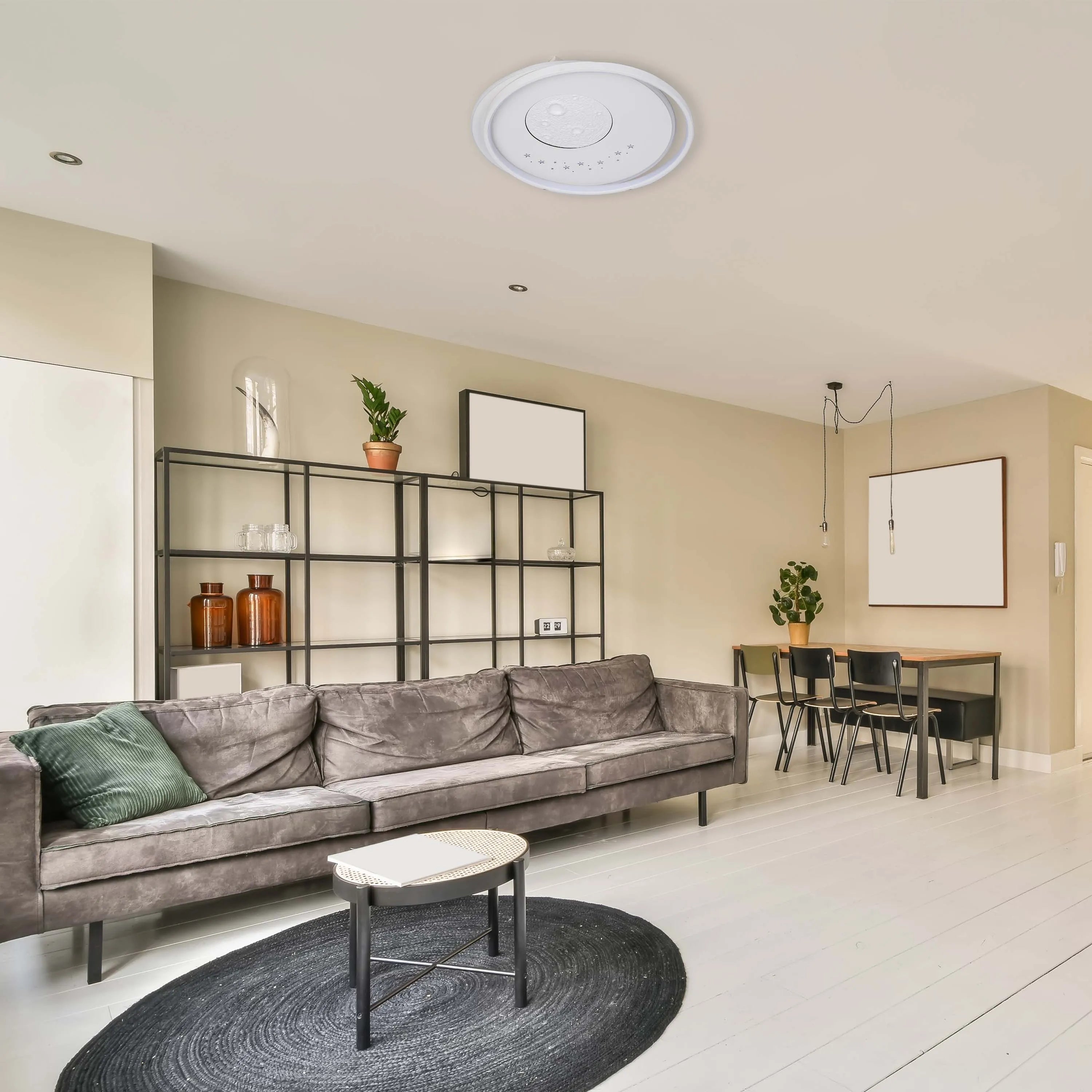 A modern living area with integrated spotlights and a feature ceiling light that boasts a lunar design with delicate star details.