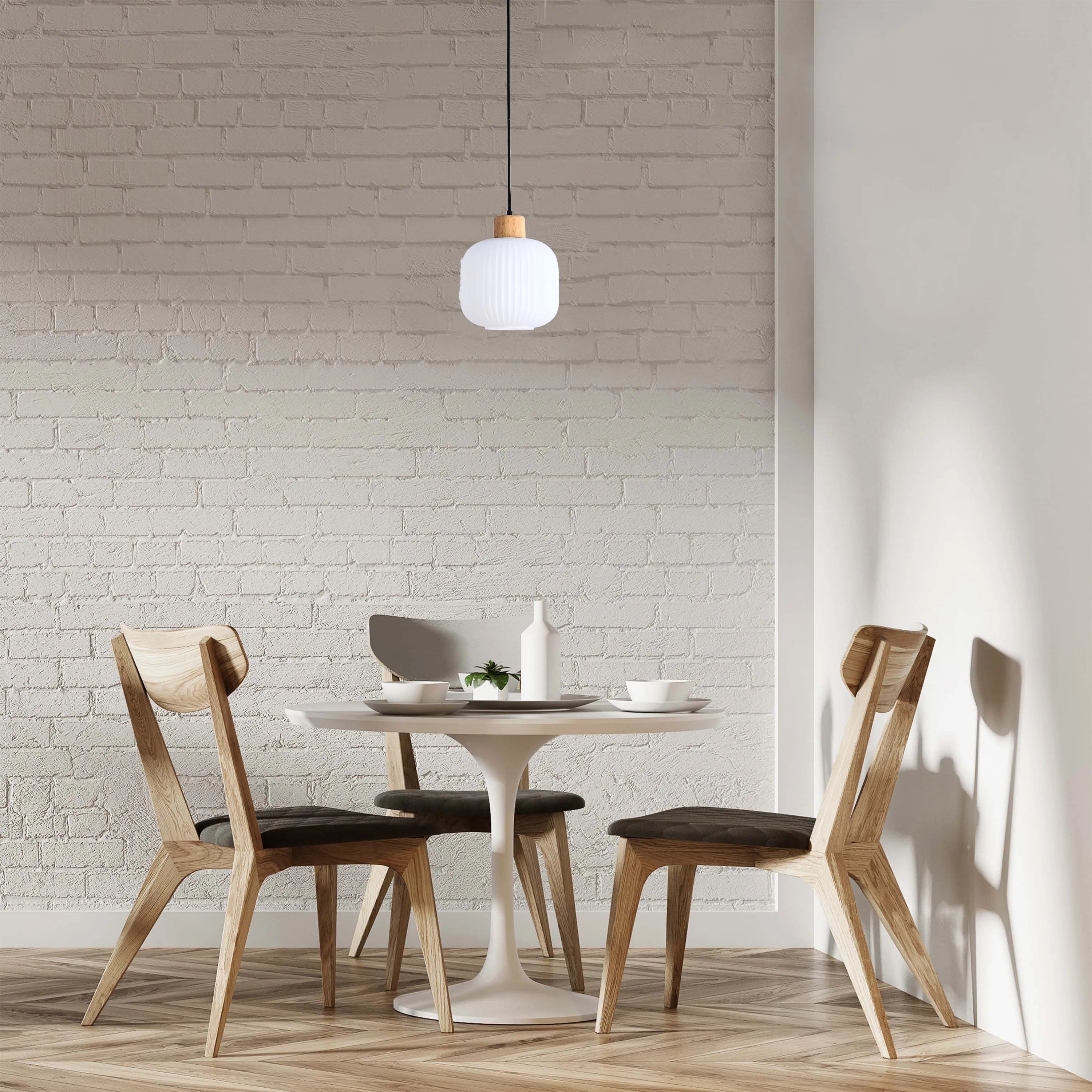 A contemporary pendant light with a white ribbed shade and wooden top, hanging above a round table in a modern dining setting.