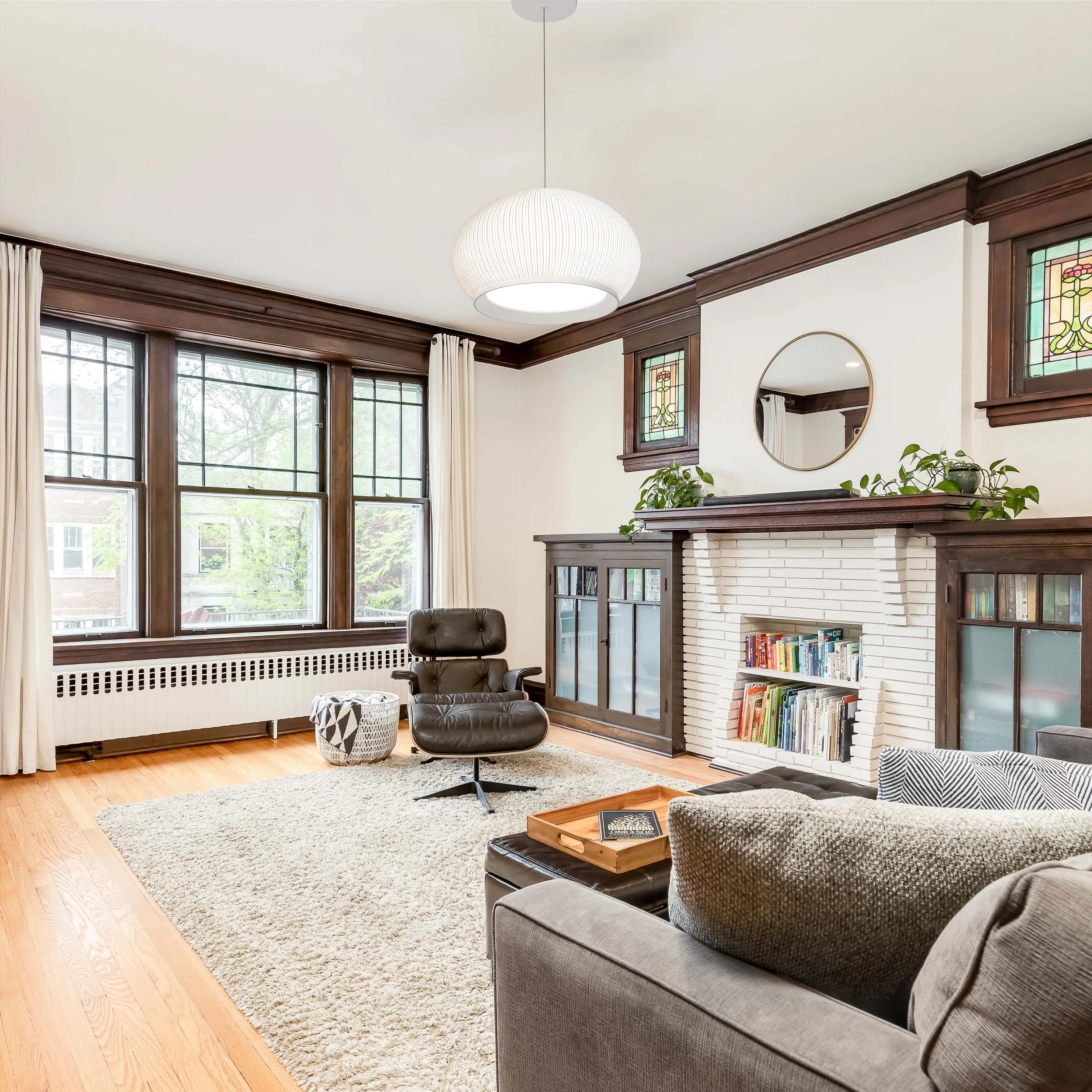 A round, woven pendant light illuminates this living room, offering a modern and stylish touch above the seating area.