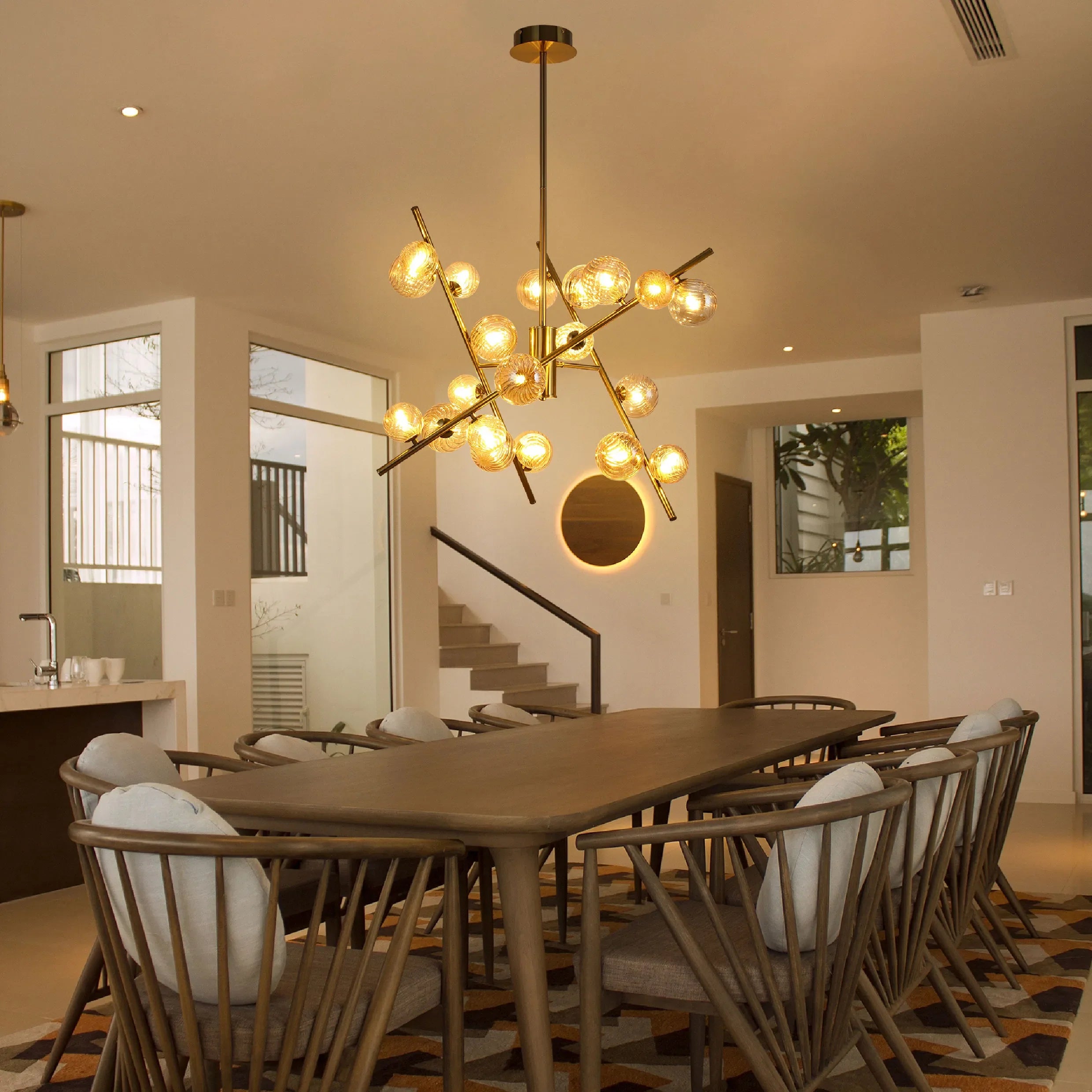 A striking gold sputnik chandelier hangs above a wooden dining table, providing warm, ambient lighting in a modern dining space.