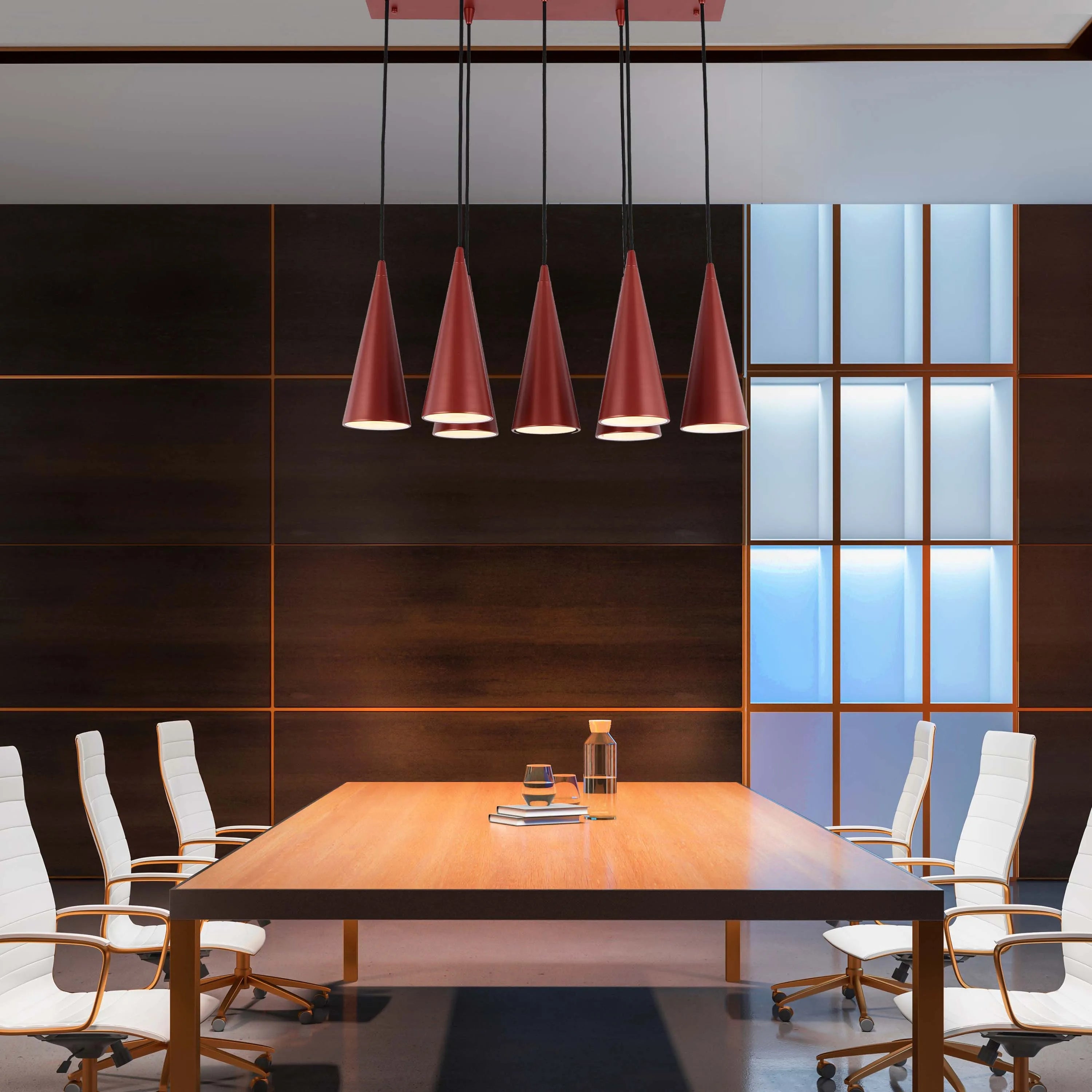 Statement lighting in a modern office space. Striking, geometric, red pendant lights hang over a wooden conference table.