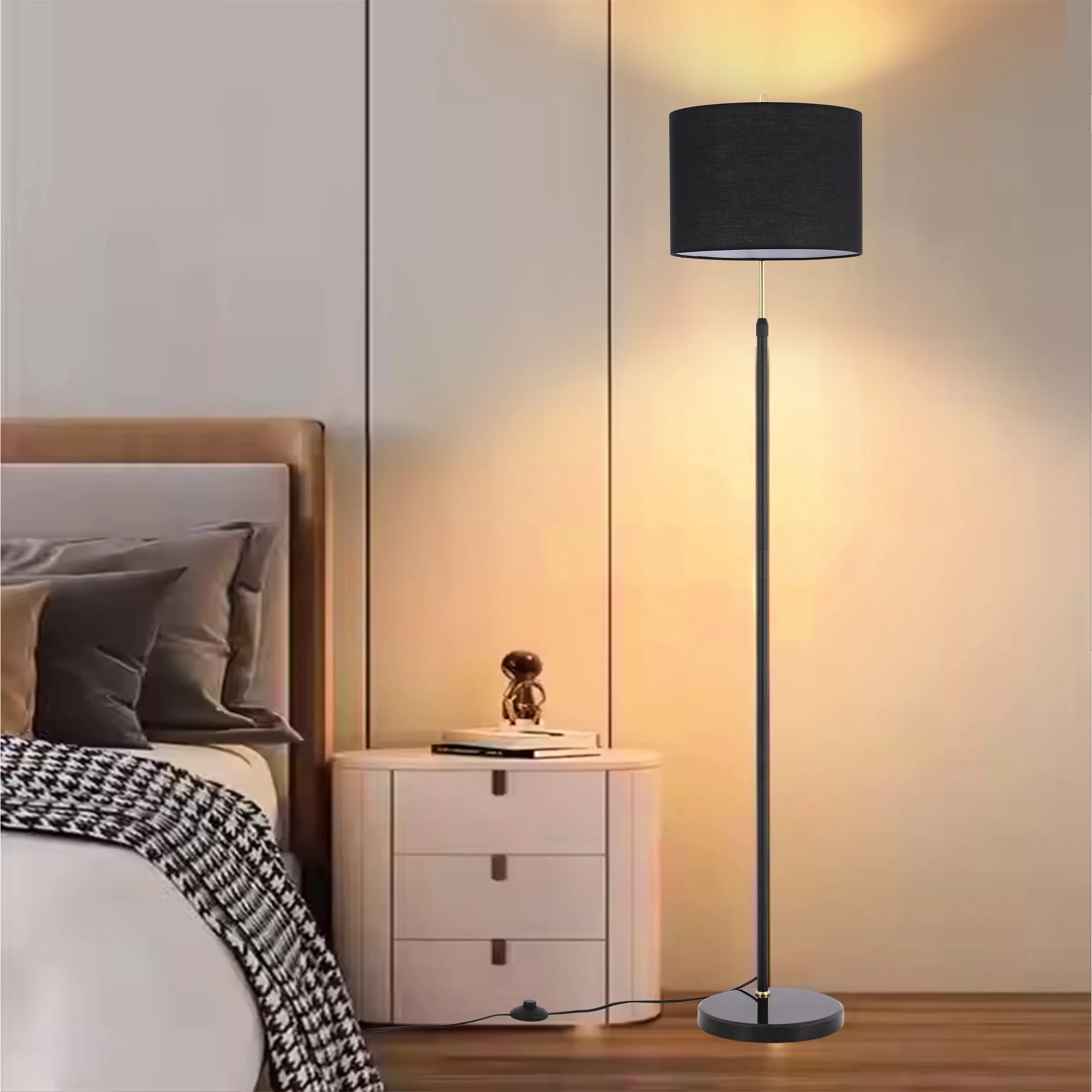 A tall, sleek black floor lamp provides ambient light in this bedroom setting, next to the bed's side table.