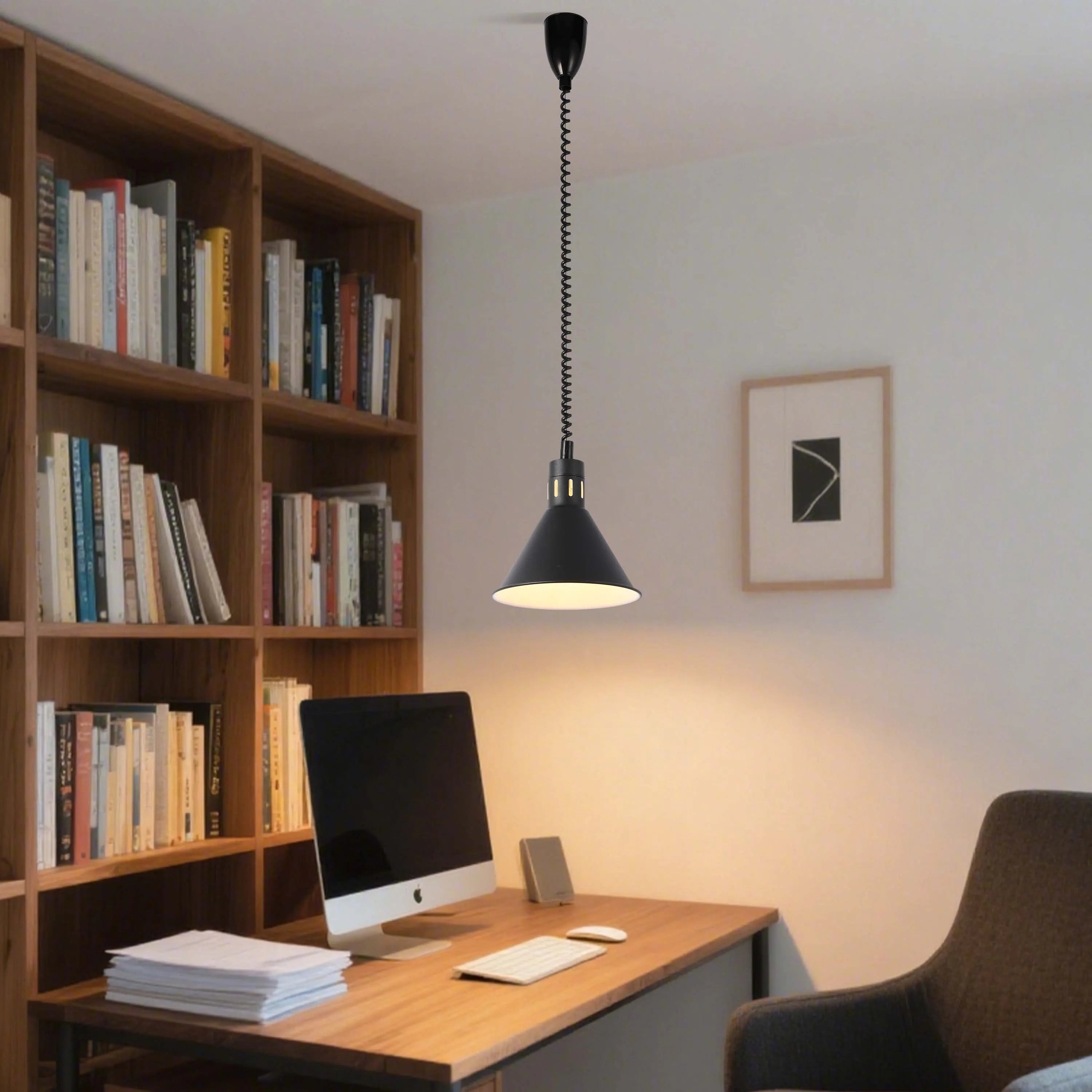 A black adjustable pendant light illuminates a desk, contrasting with the bright light spilling from within.
