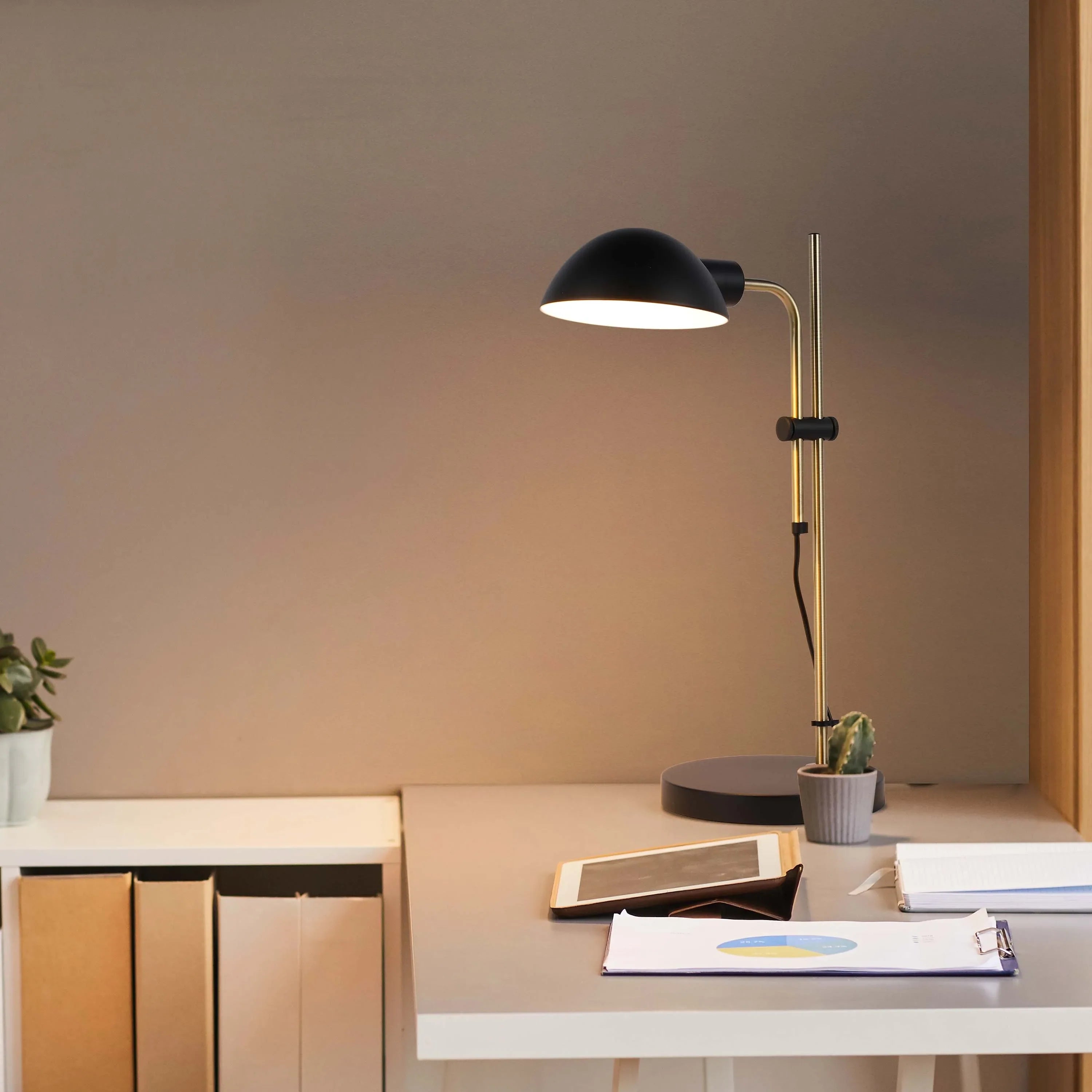 A contemporary desk lamp illuminates a workspace with a warm glow, highlighting documents and adding a touch of modern elegance.