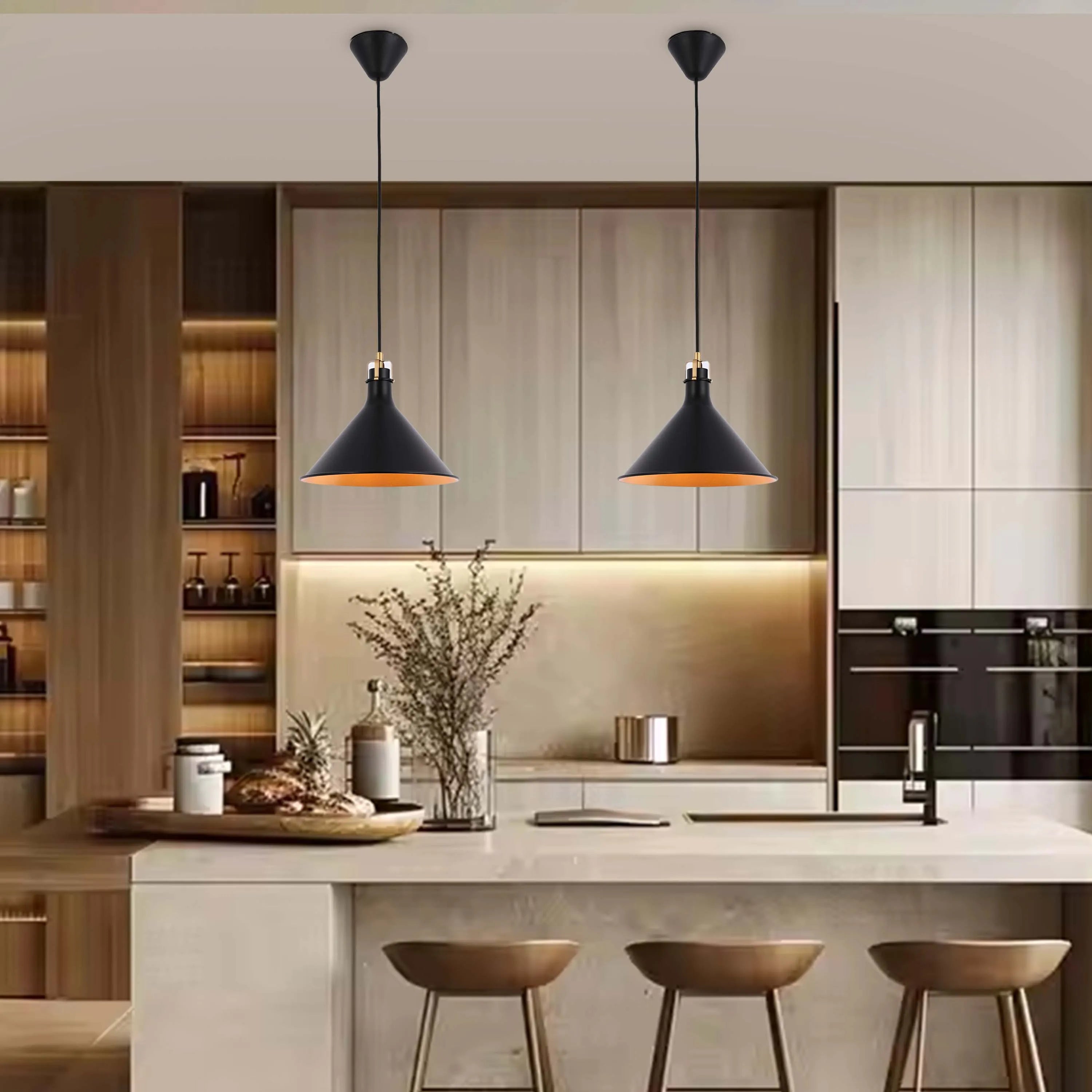 Two modern pendant lights hang over a kitchen island, casting a warm glow. Black metal shades with gold interiors add a stylish touch.