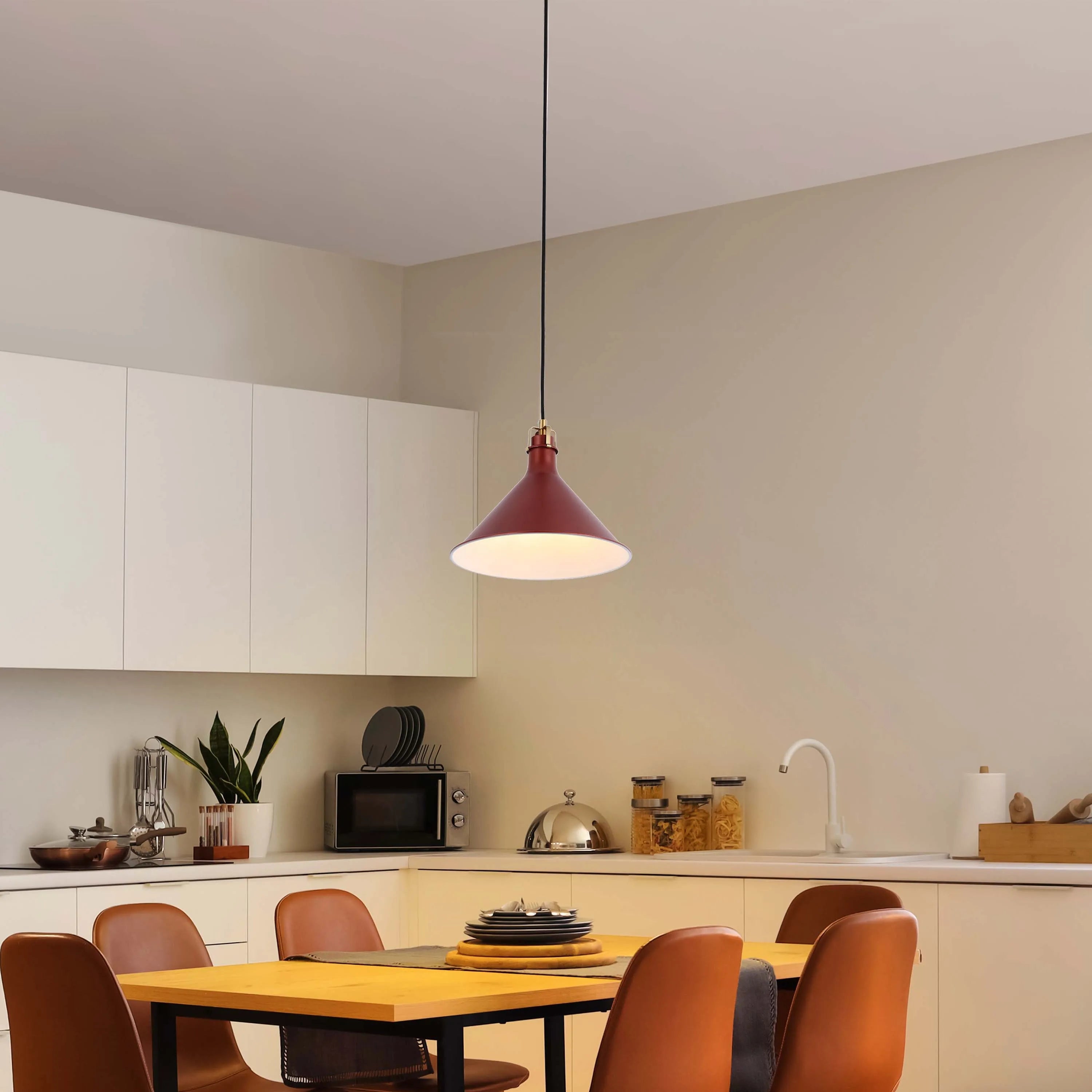 A red pendant light hangs over a wooden dining table in a bright, modern kitchen. The light casts a warm glow over the room.