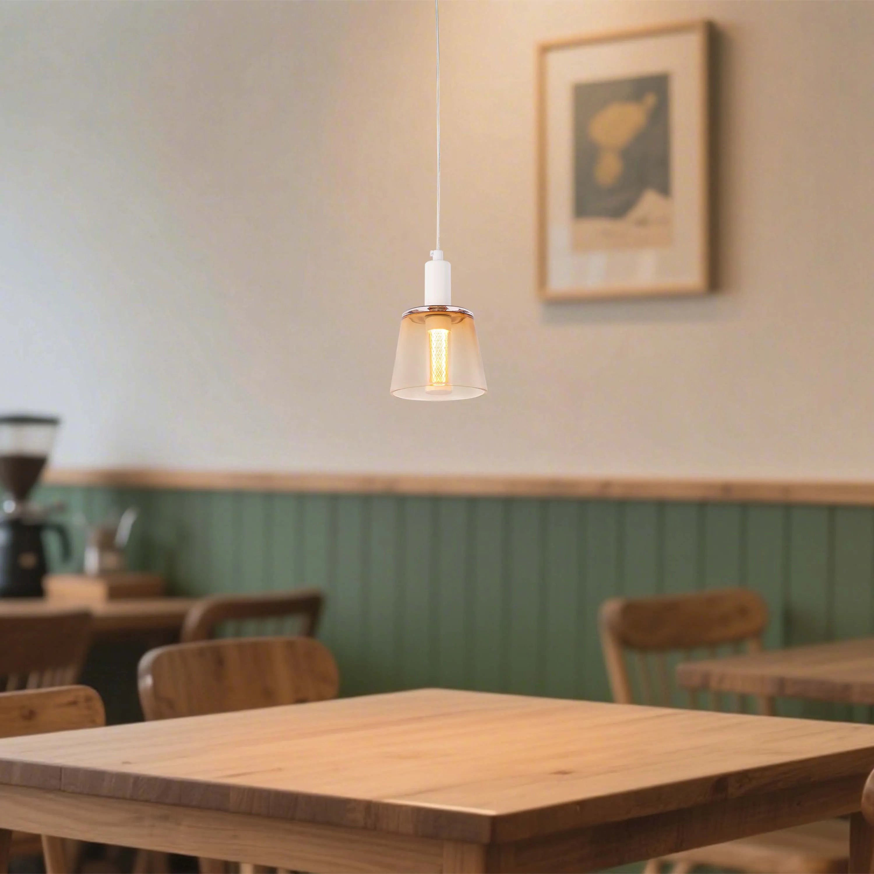 A stylish amber glass pendant light hangs above a wooden table, creating a warm and inviting ambience in a cafe setting.