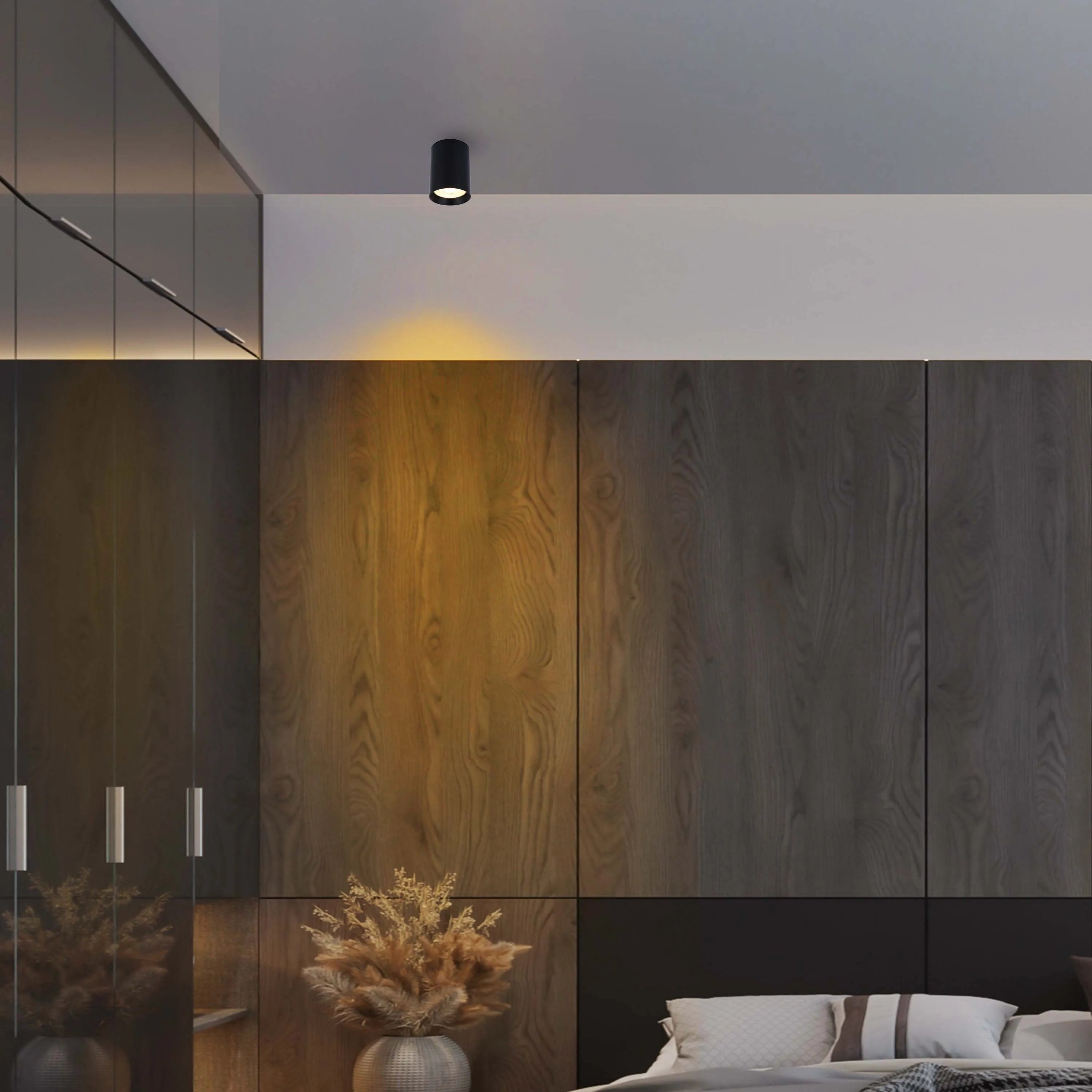 A modern interior featuring a sleek, black cylindrical ceiling light that casts a warm glow.