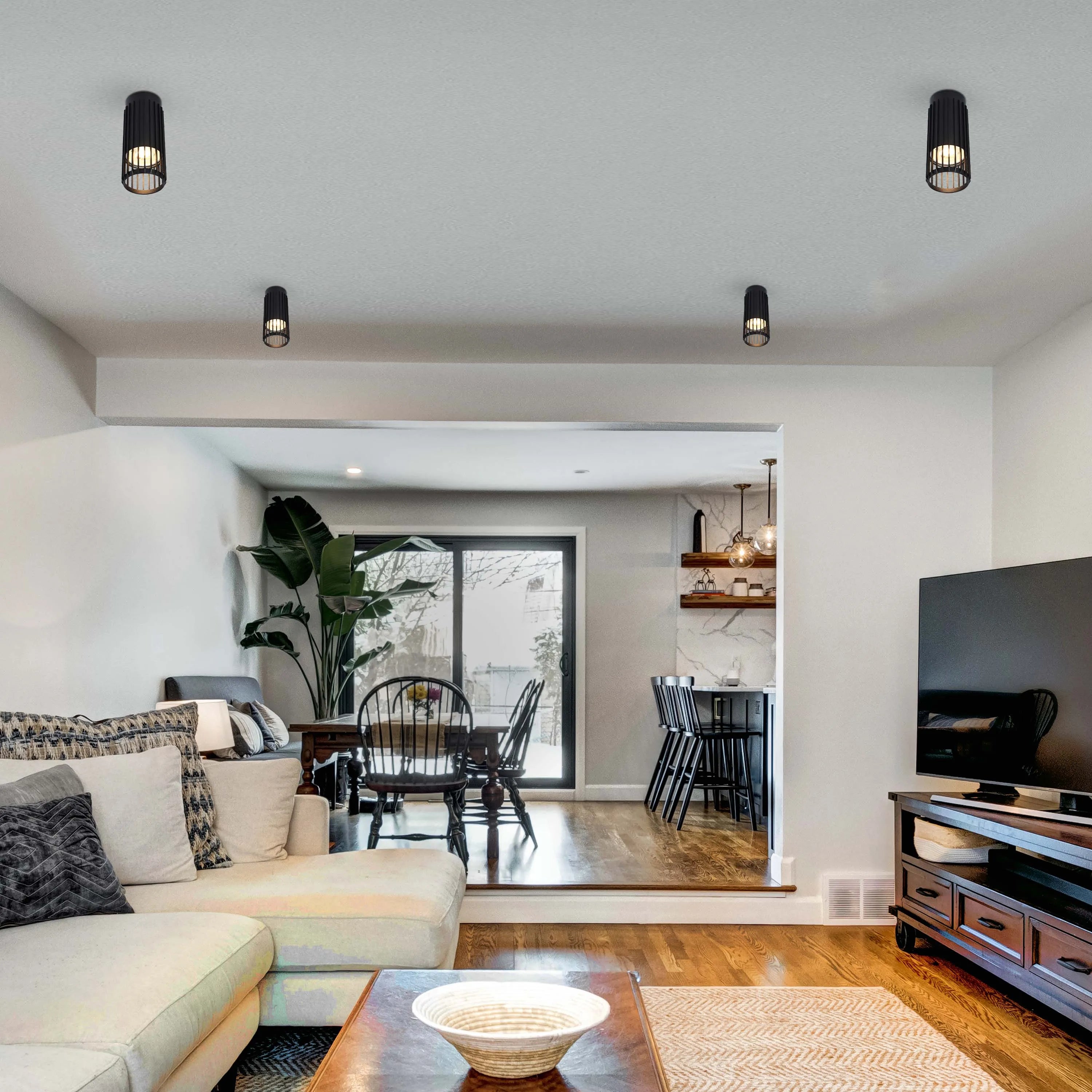 Four modern, black, cage-style ceiling lights illuminate the room. Stylish and functional lighting for any contemporary space.