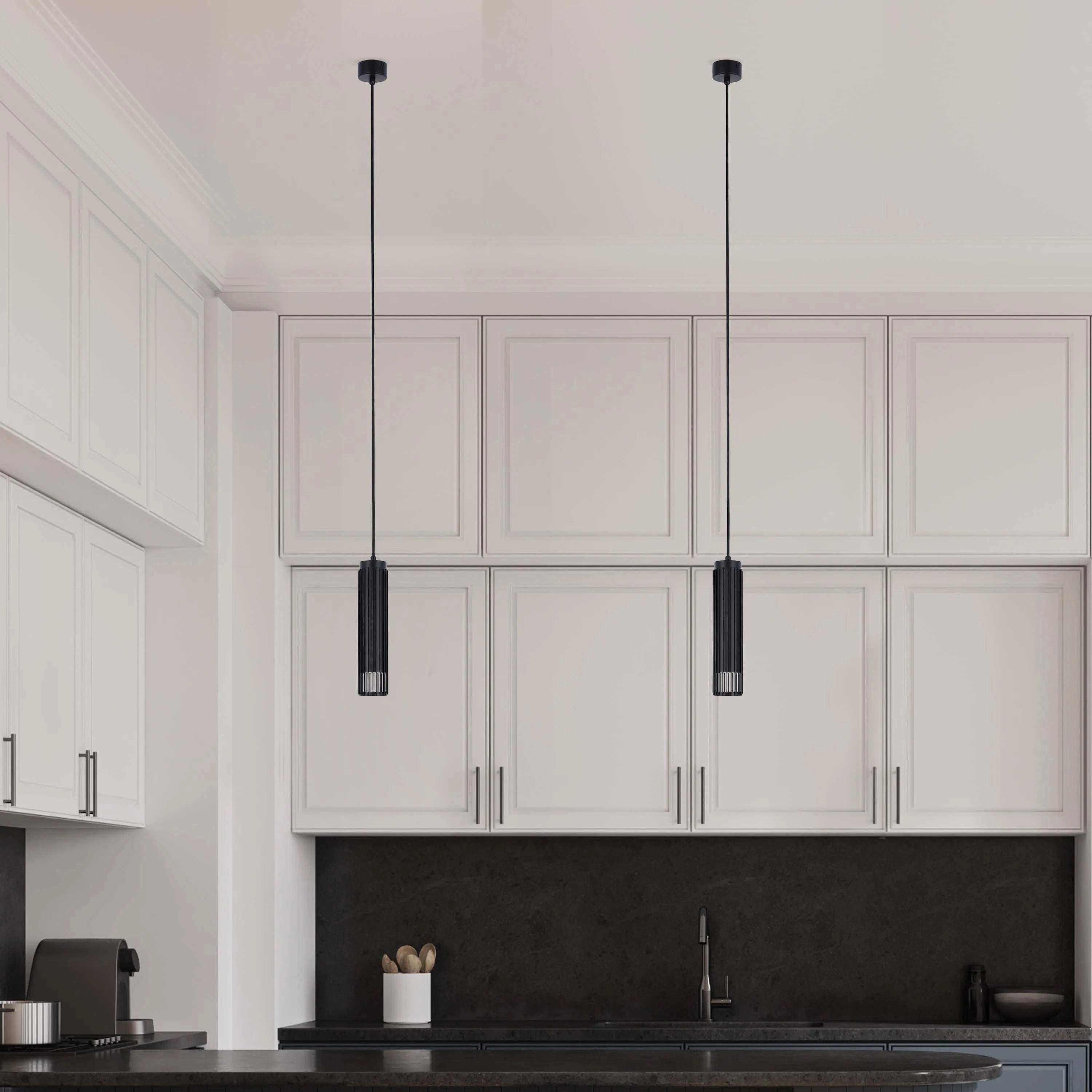 Two pendant lights with black cylindrical shades hang above a modern kitchen island, adding a touch of elegance and focused illumination.