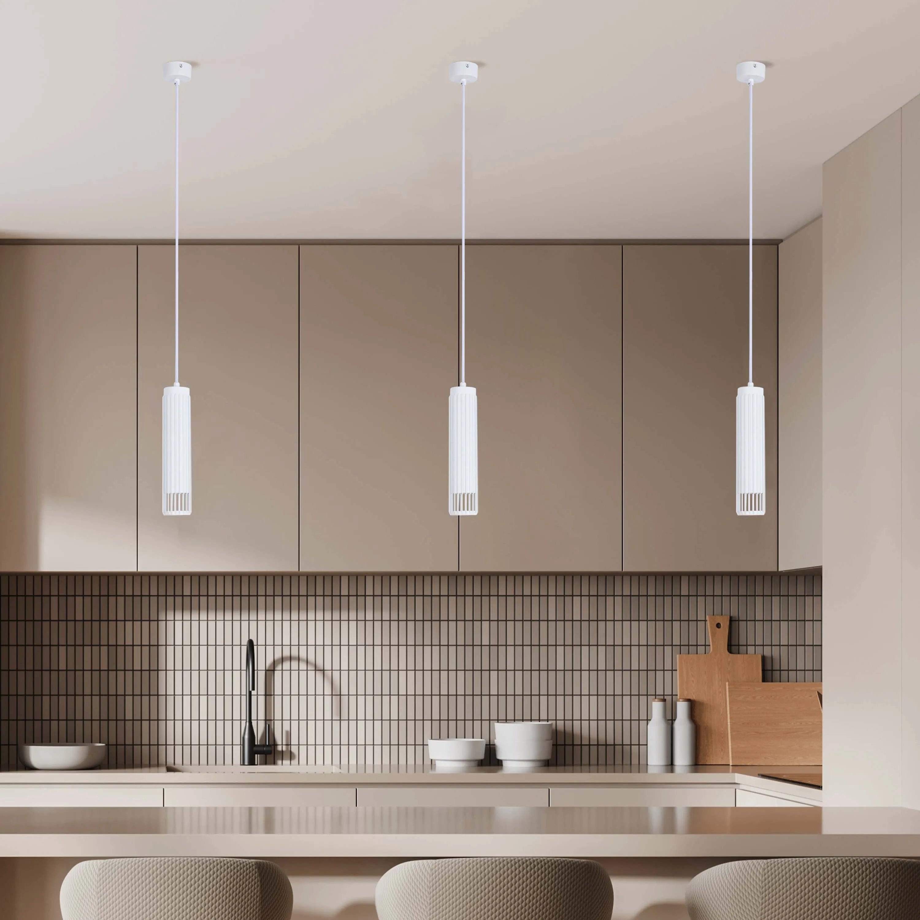 Three modern, cylindrical, white pendant lights hang above a kitchen island, illuminating the space with style and elegance.
