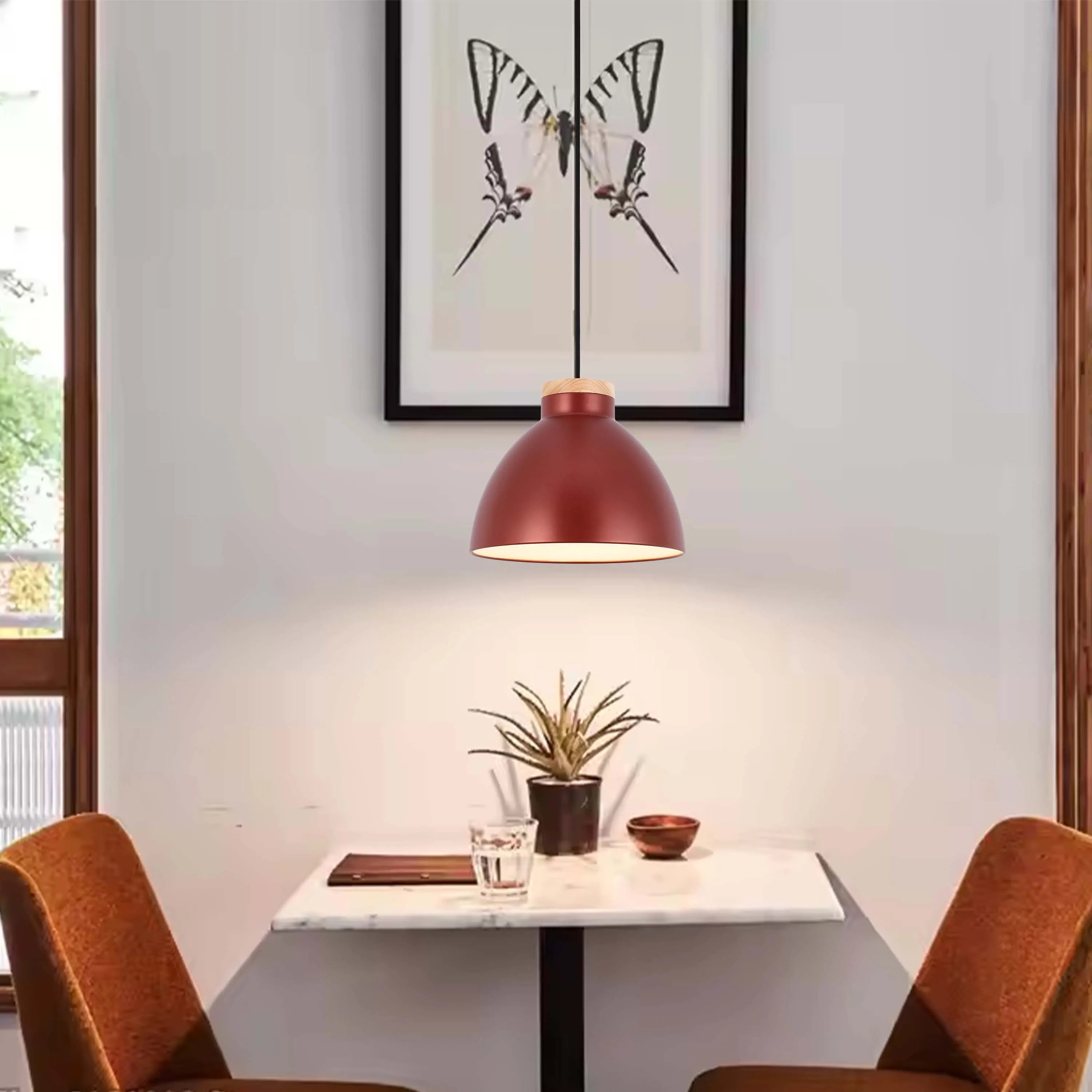 A stylish, red dome pendant light hangs over a table with two chairs, casting a warm glow and adding a modern touch to the room.