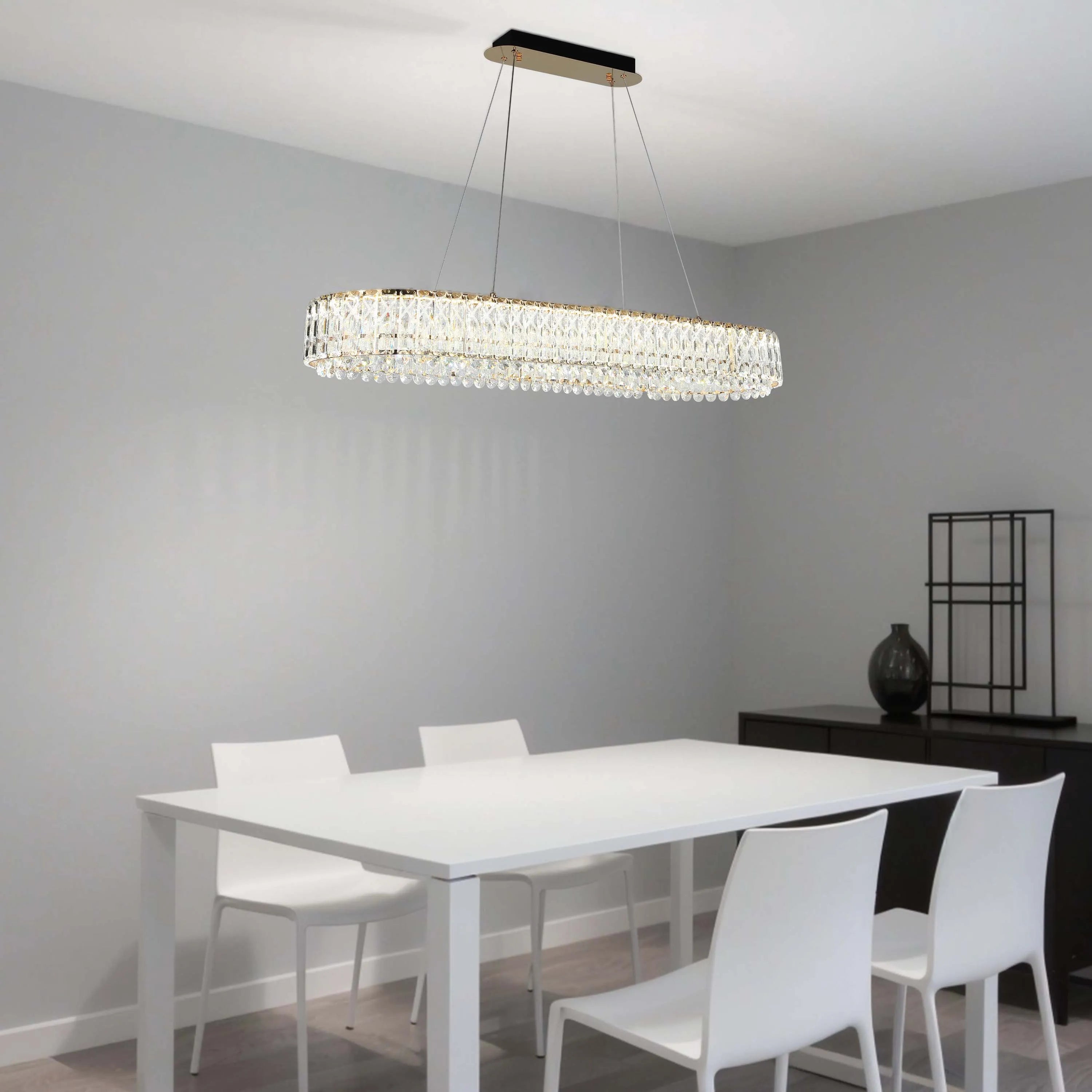A modern crystal chandelier hangs above a dining table. The fitting has a rectangular shape and offers a touch of glamour to the room.