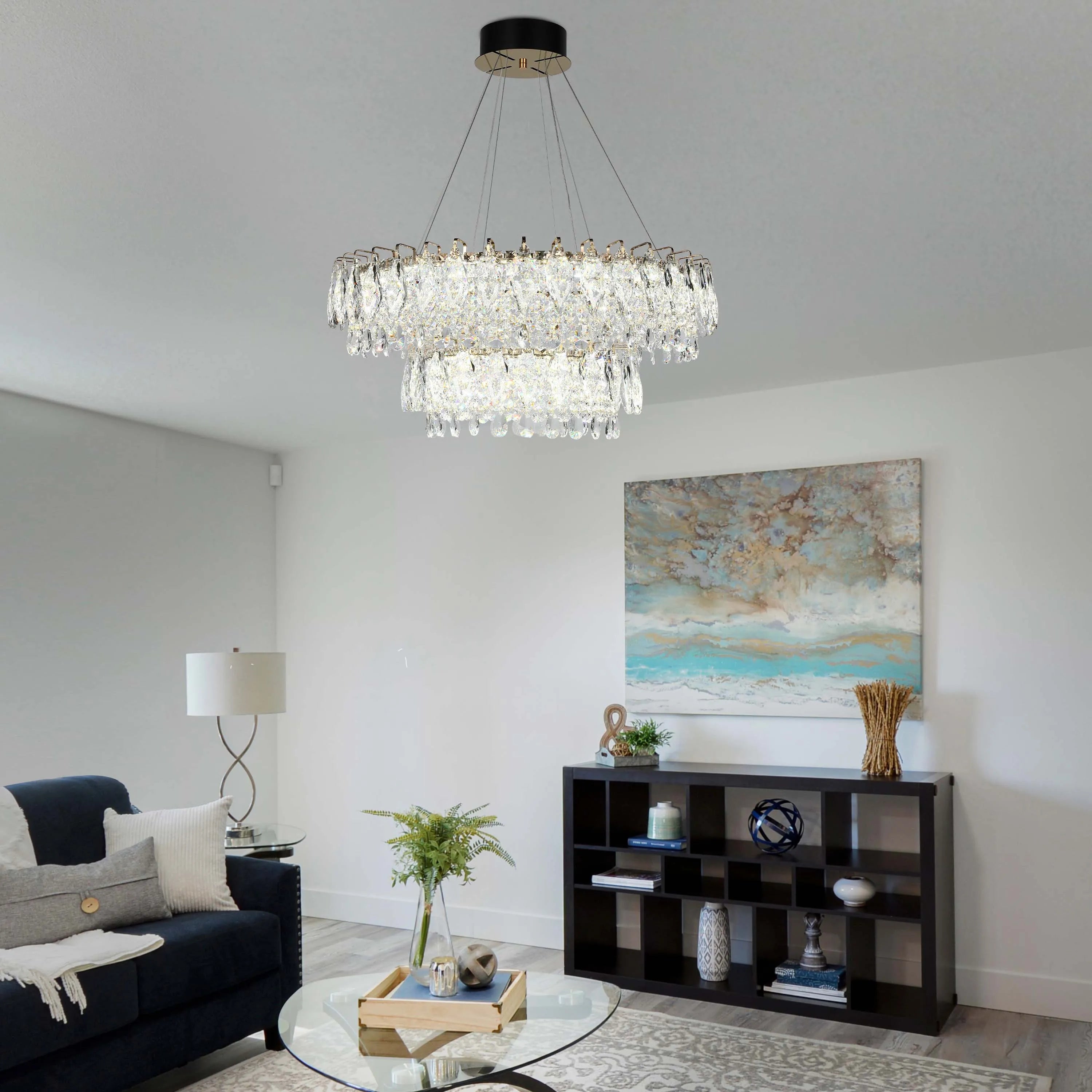 A stunning two-tier crystal chandelier hangs above a stylish living room, illuminating the space with elegance and a soft glow.