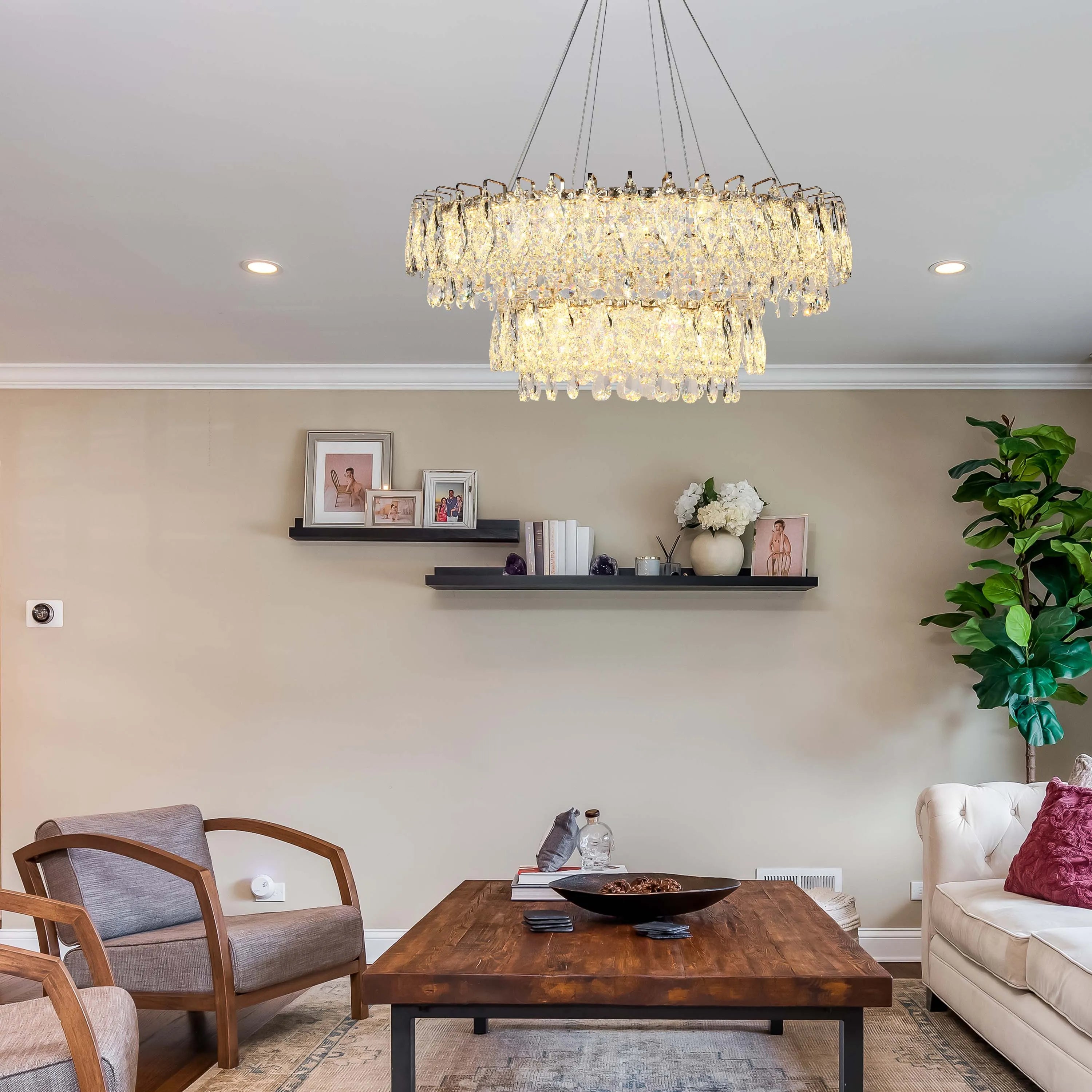 A stunning, two-tiered crystal chandelier hangs above a living room, providing warm, ambient light.