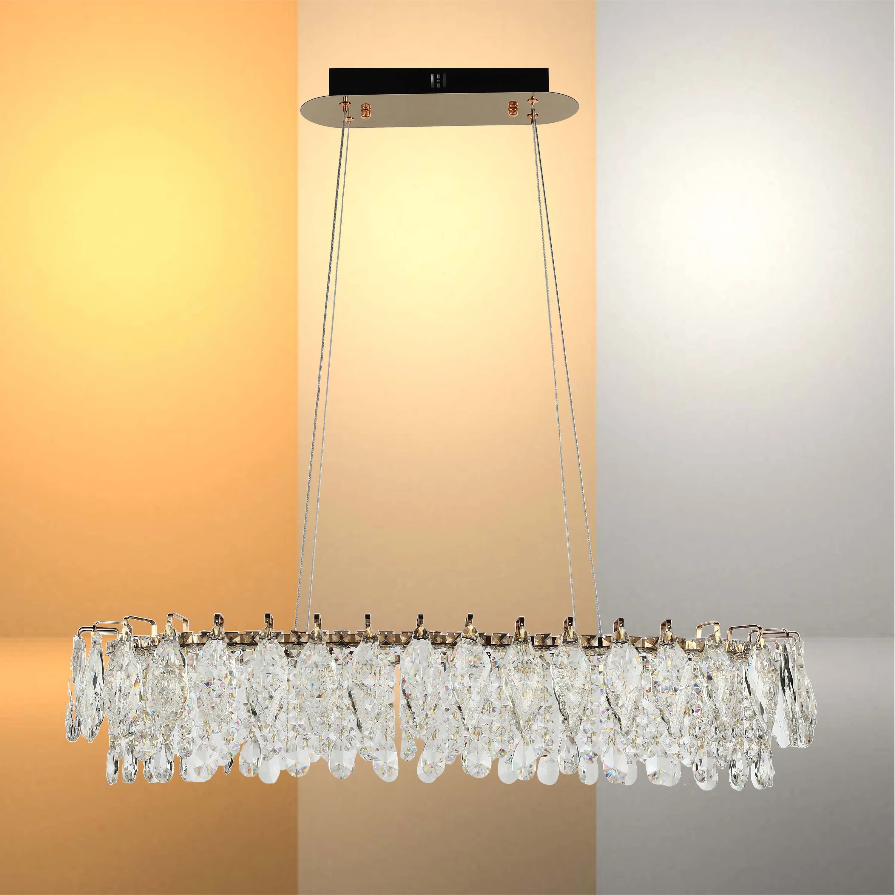 A modern crystal chandelier with a rectangular shape, suspended by wires. It gives off a warm glow.