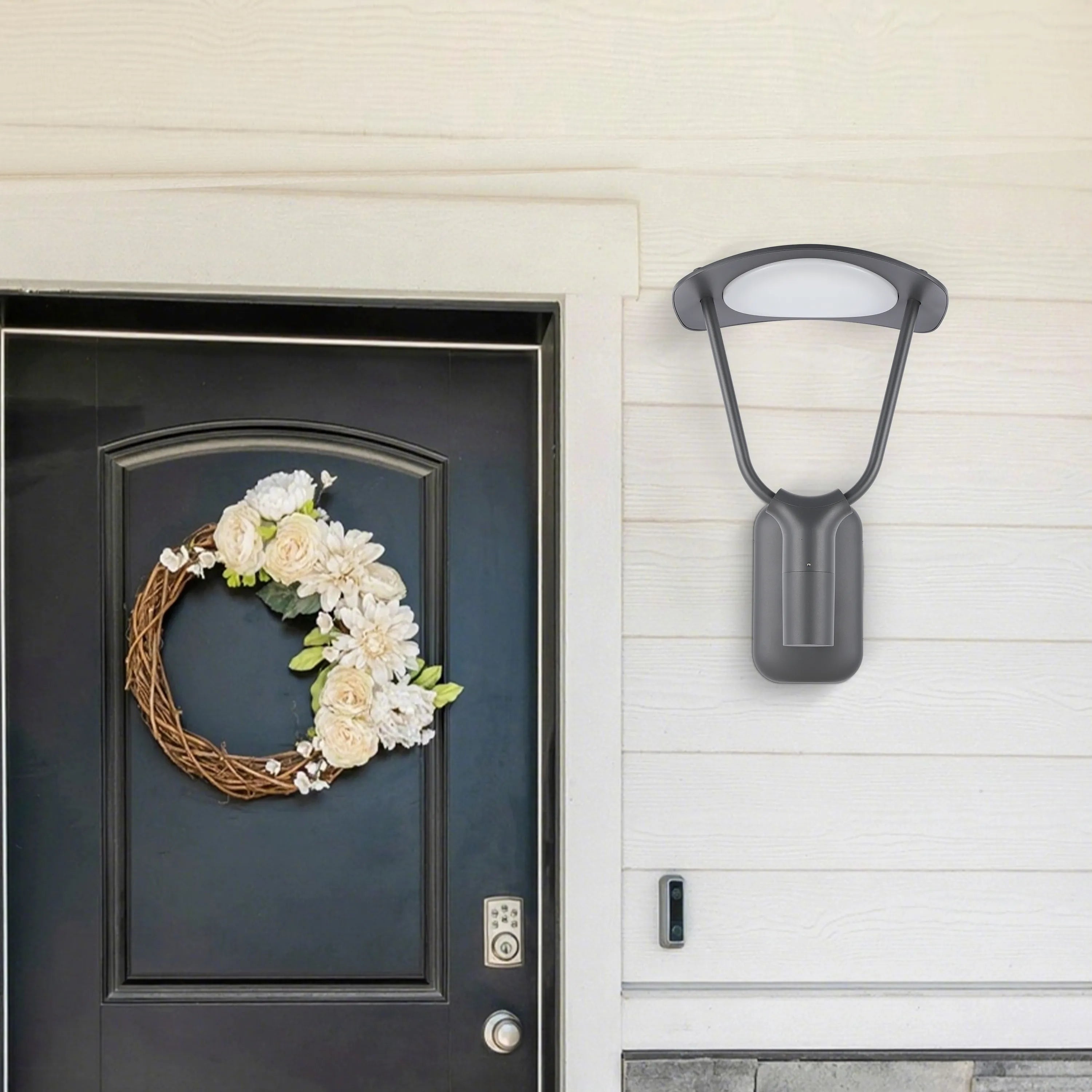 A modern, dark grey outdoor light fixture with a white LED panel, mounted on a white-painted, horizontally-panelled wall.