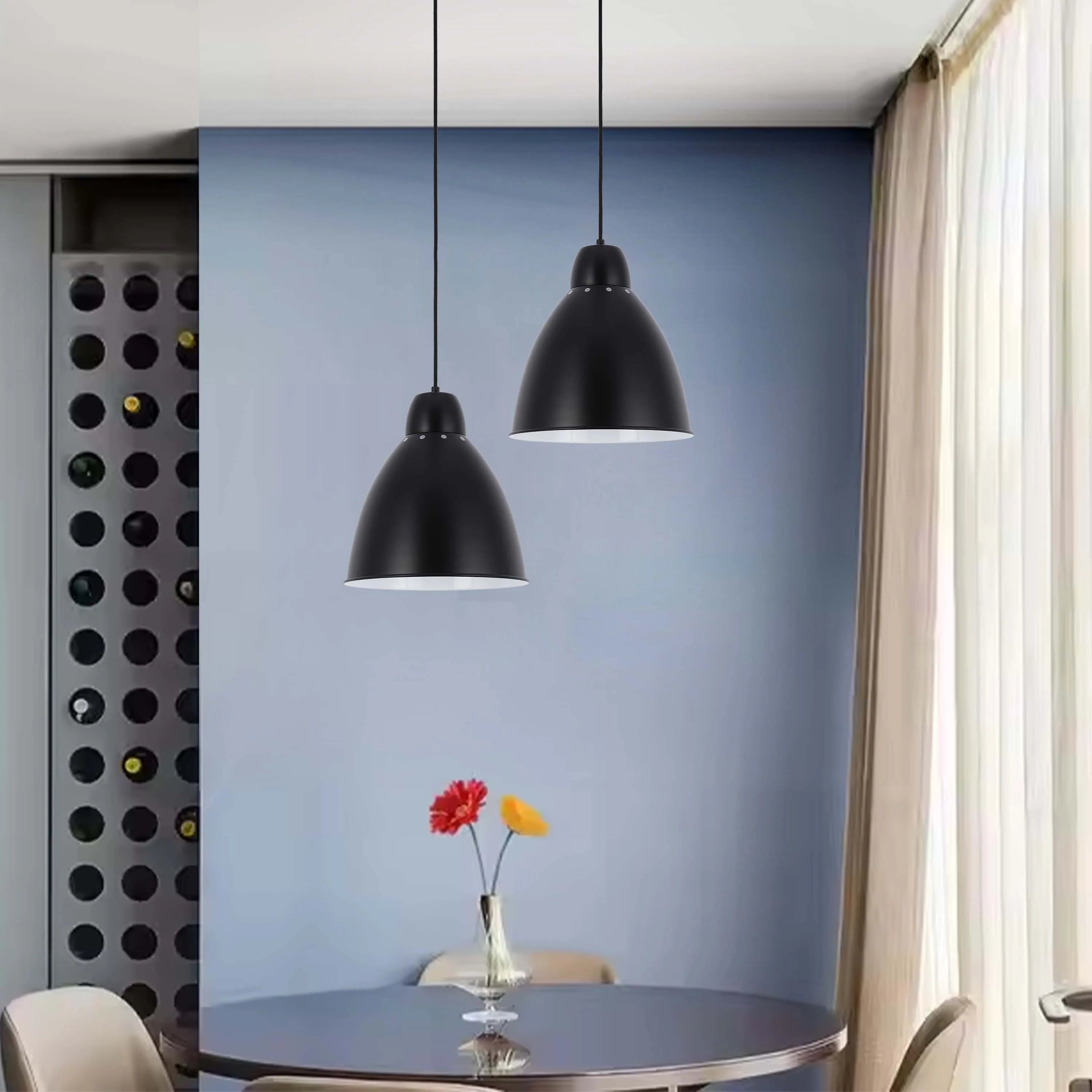 Two black pendant lights hang above a dining table with a vase of flowers, creating a modern and stylish lighting feature.
