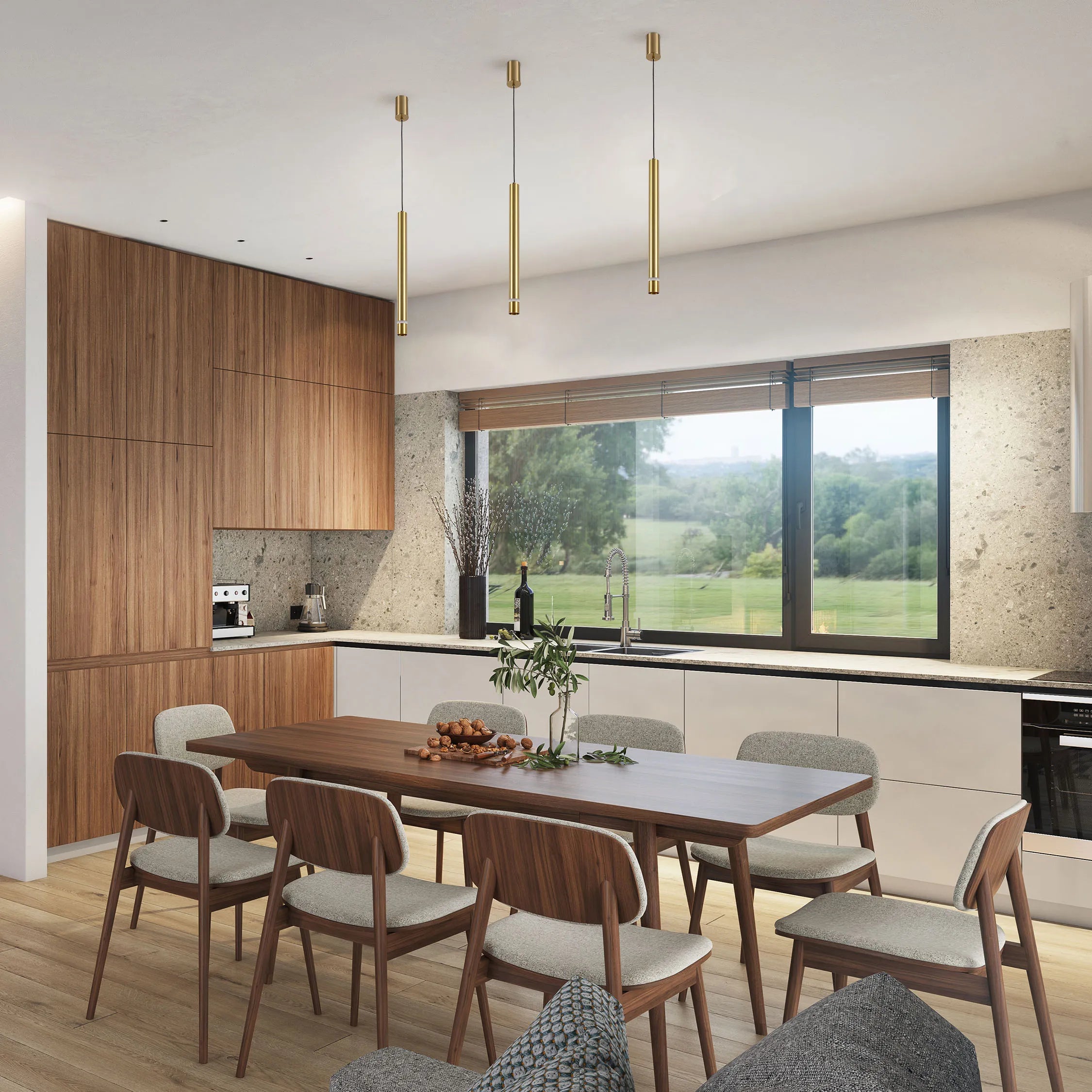 Modern kitchen with three sleek, gold pendant lights suspended above a wooden dining table. The room is bright and airy with natural light.