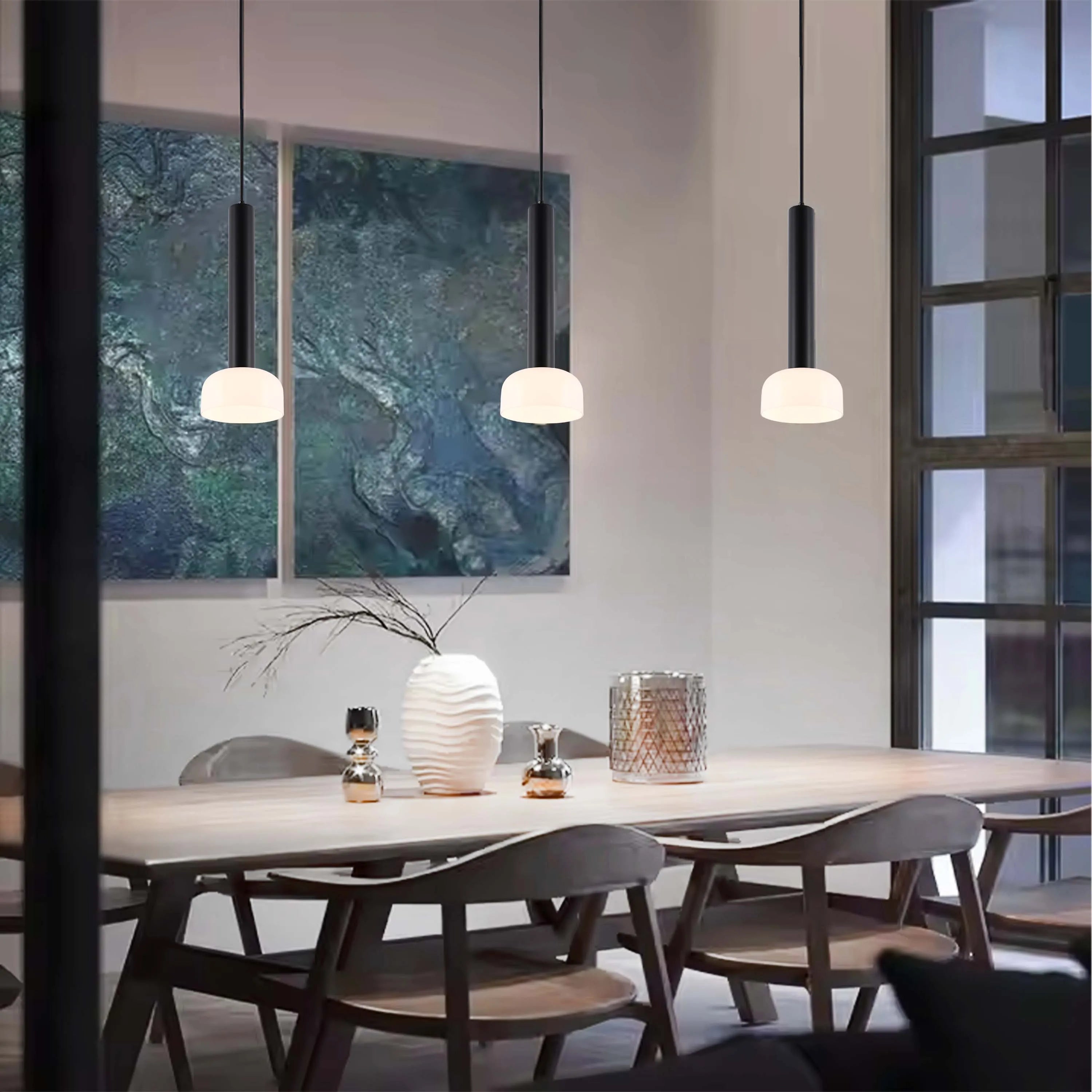 Three pendant lights with black shades hang over a wooden dining table, providing a warm, inviting glow to the dining space.