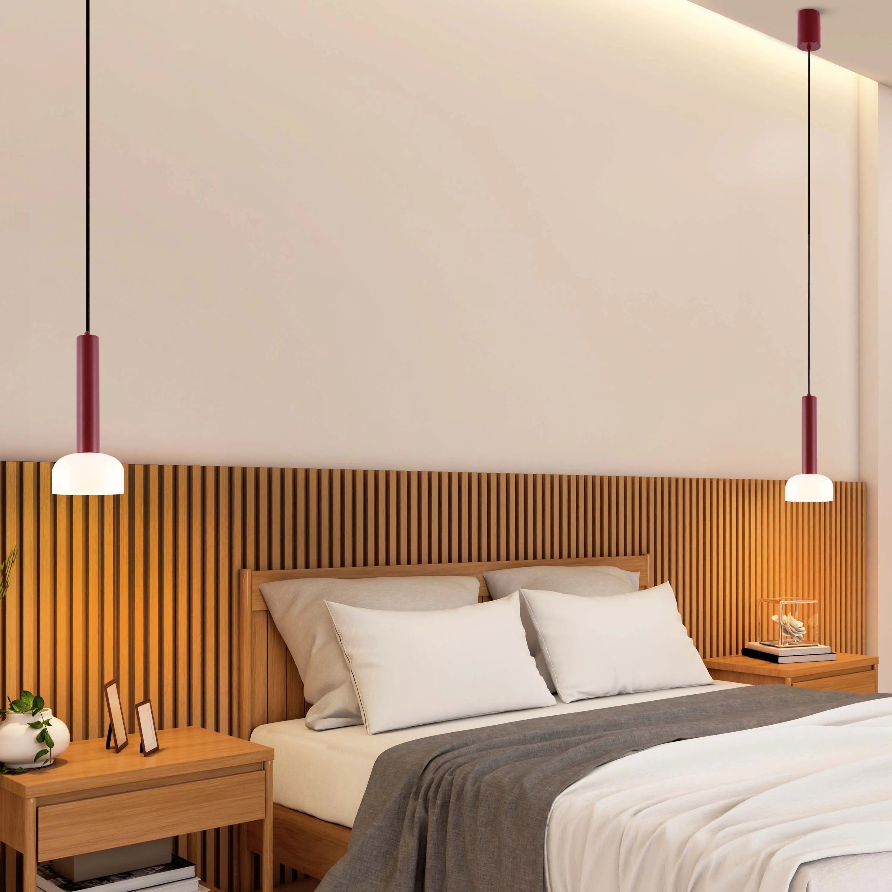 A modern bedroom features two pendant lights with a cylindrical, burgundy fixture and a round, opal glass shade, suspended by black cables.