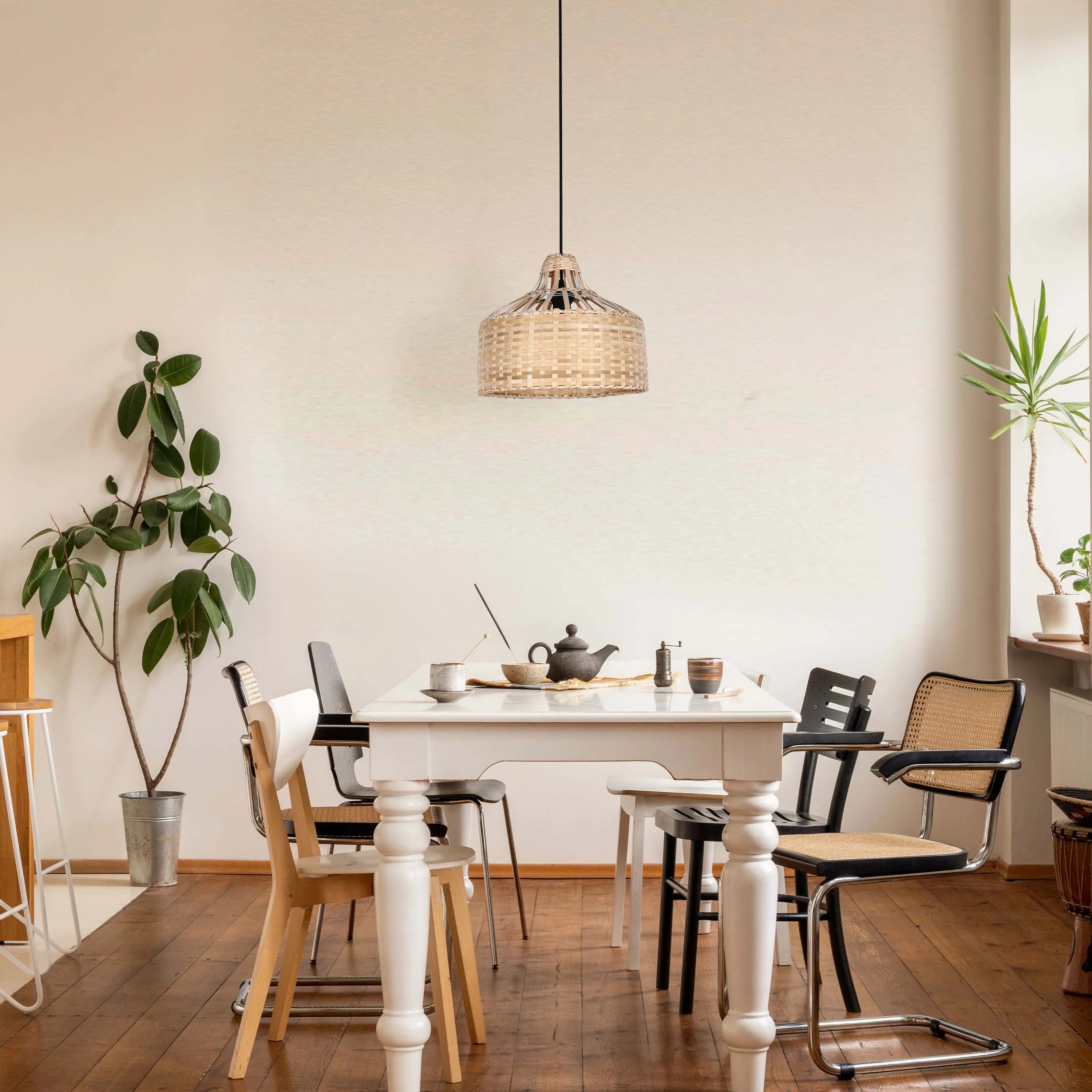 Wicker pendant light hanging above a dining table, casting a warm, ambient glow. Natural light also fills the room.