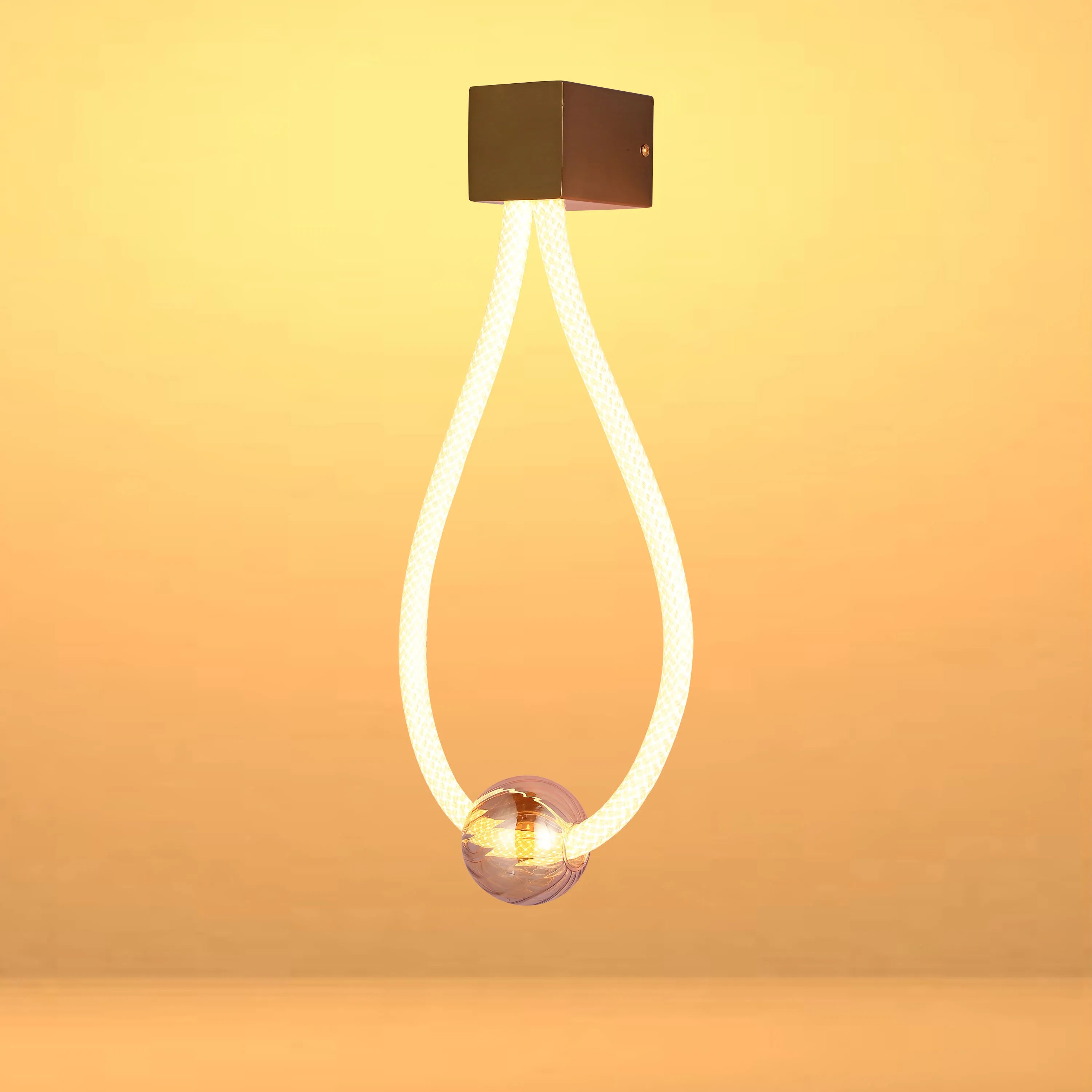 A modern ceiling light featuring a rope-like loop, culminating in a sphere, emitting a warm, ambient glow.