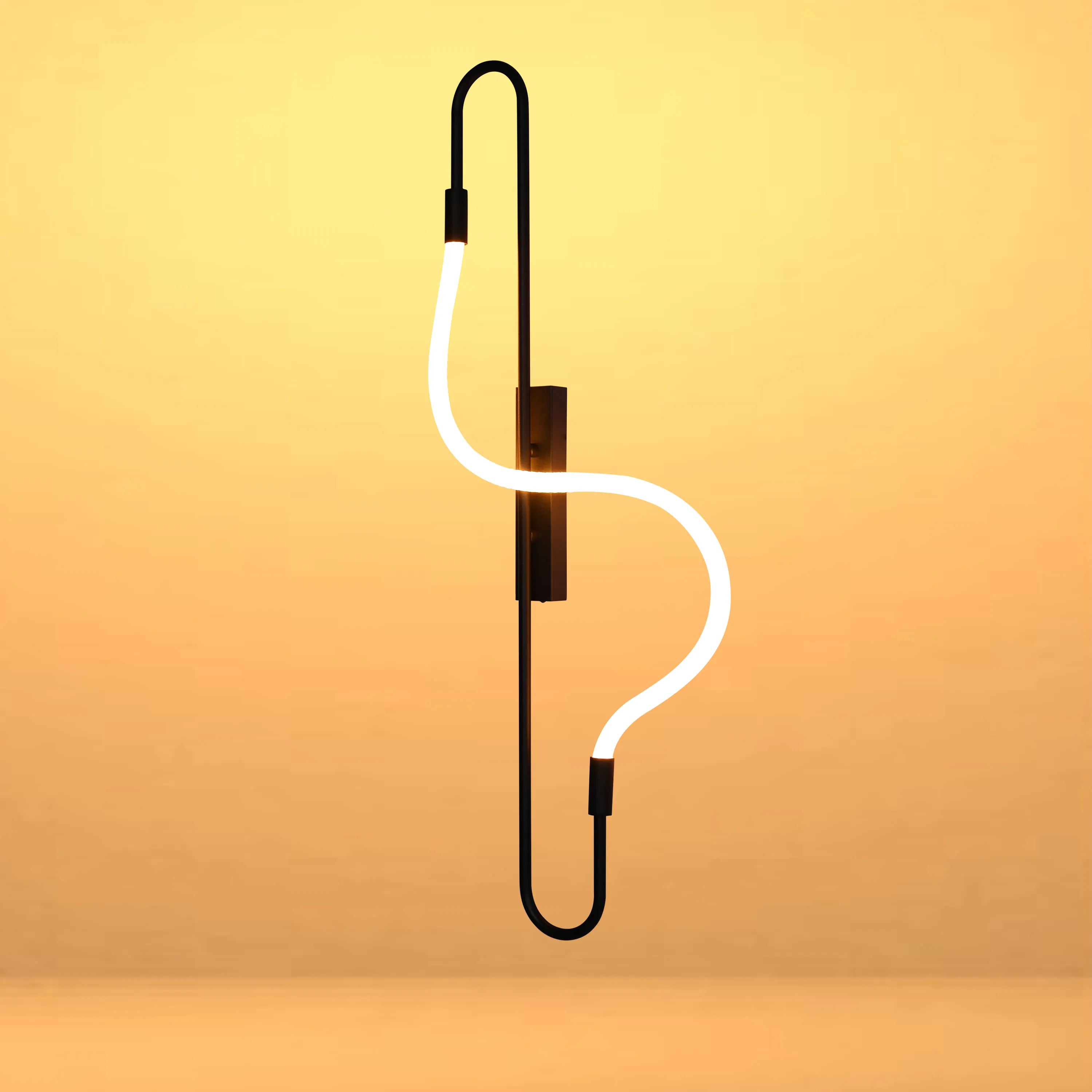 A contemporary wall light featuring a sleek black frame with a curvaceous LED light tube, casting a warm glow.