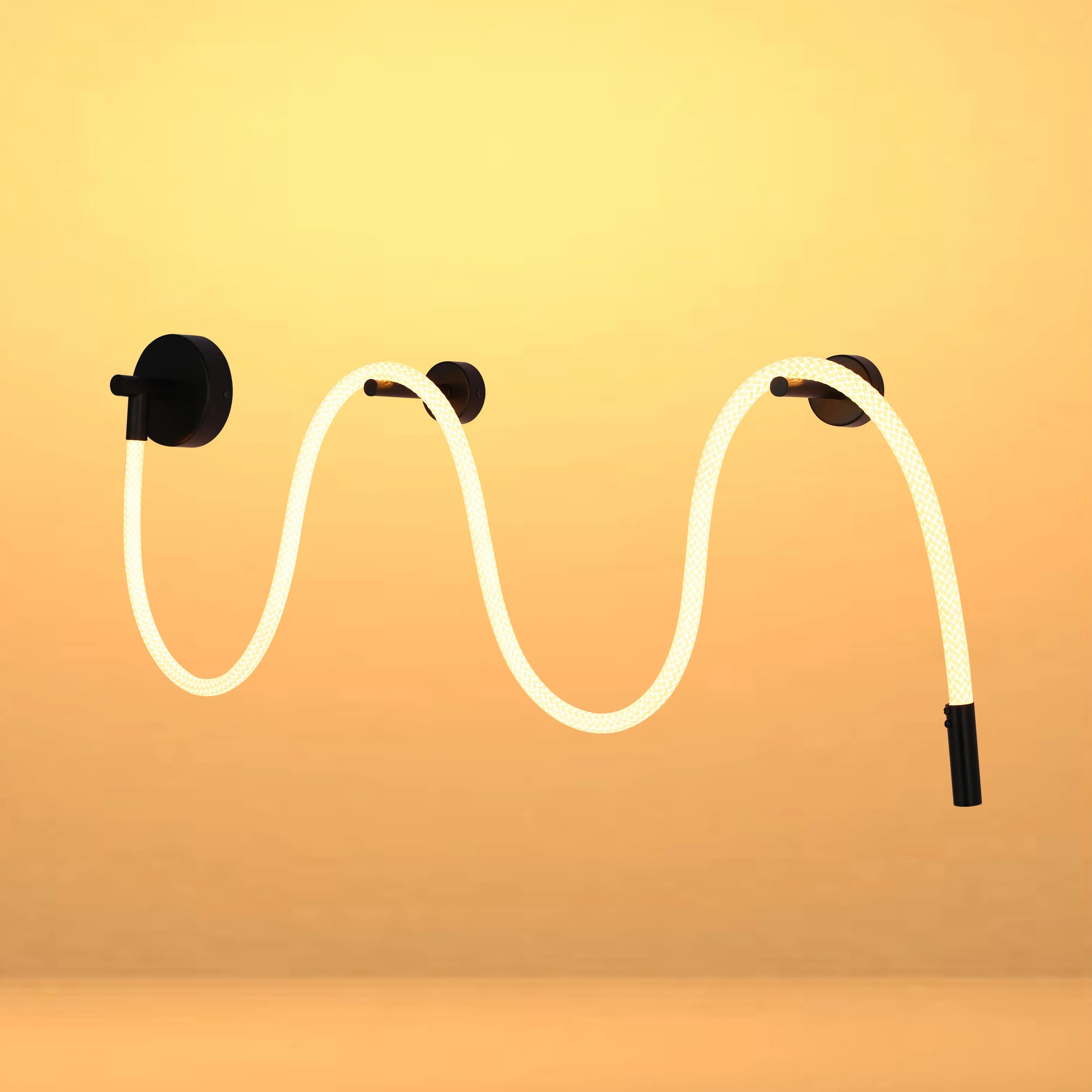 A modern wall light fixture with a flexible, illuminating cord attached to matte black mounting points.