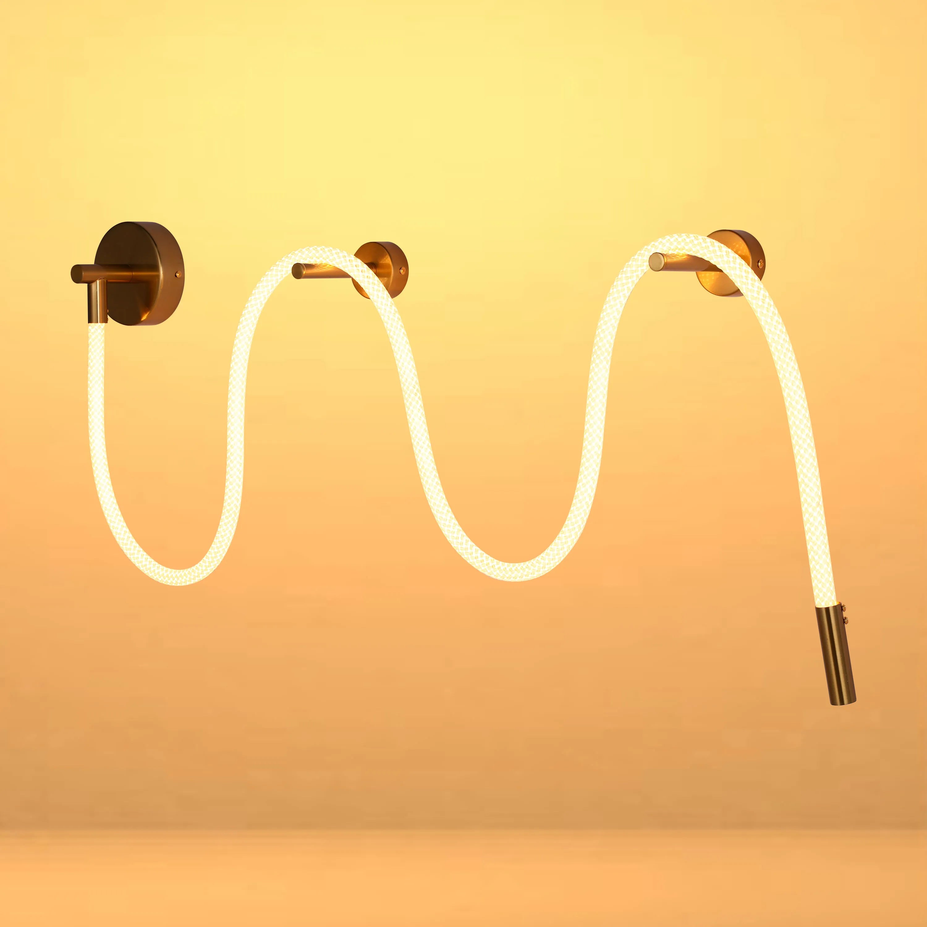 A modern, wavy wall light fixture with bronze fixings and a diffused, linear light source creates a warm, inviting ambiance.