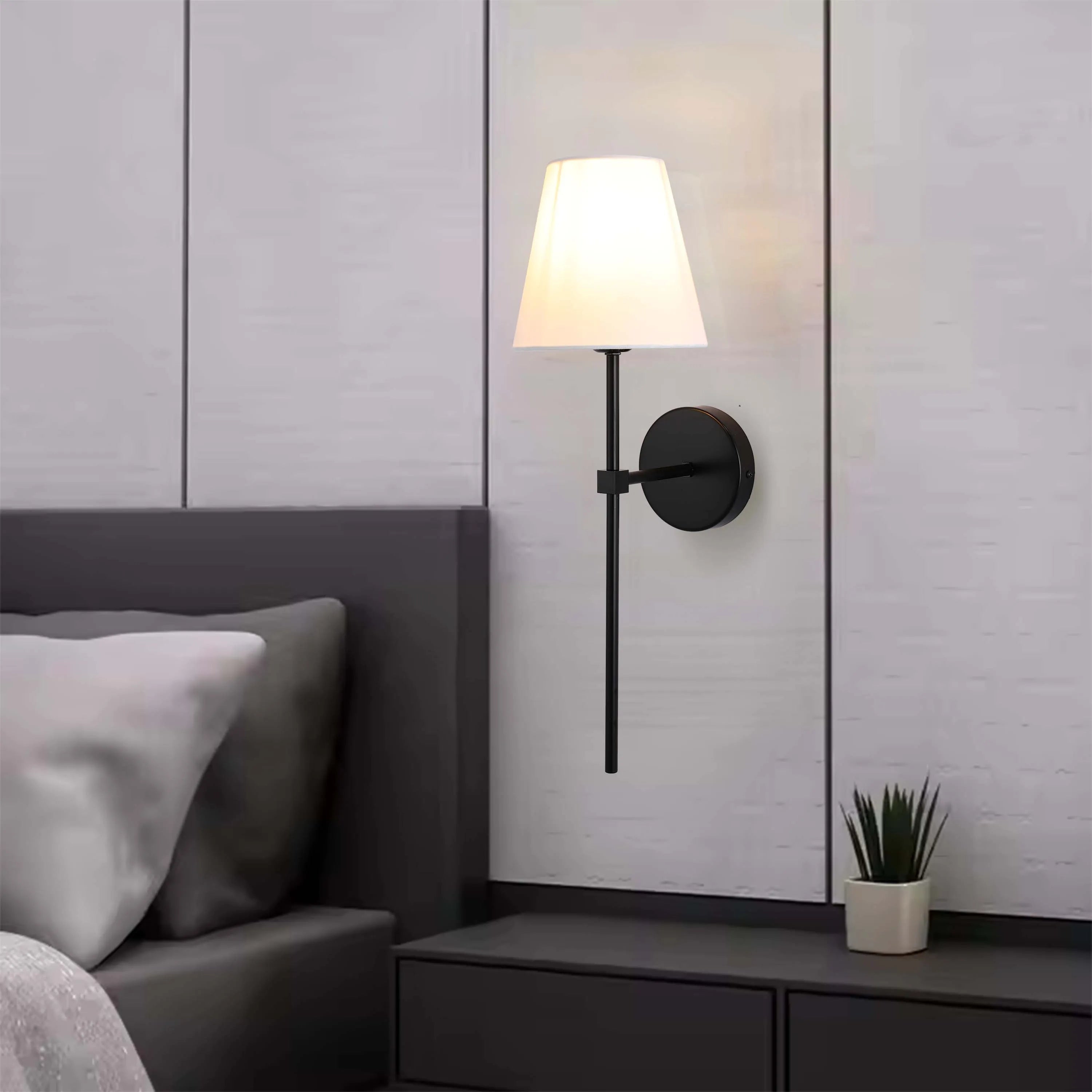 A stylish wall lamp featuring a white lampshade, a long black stem, and a circular mount - perfect for adding a touch of elegance.
