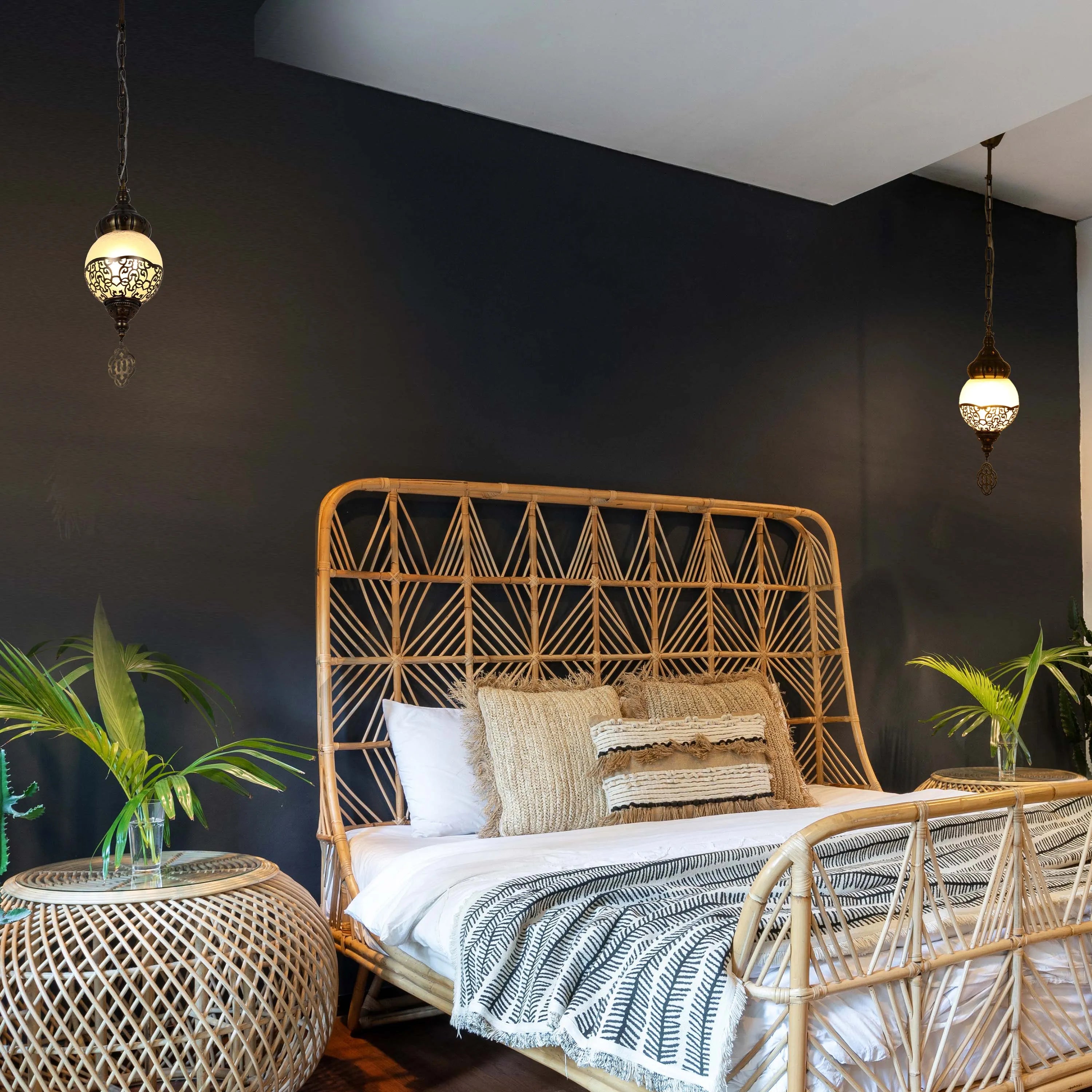 A bedroom with wicker furniture is lit by ornate pendant lights, creating a cosy, inviting ambience with warm, ambient lighting.