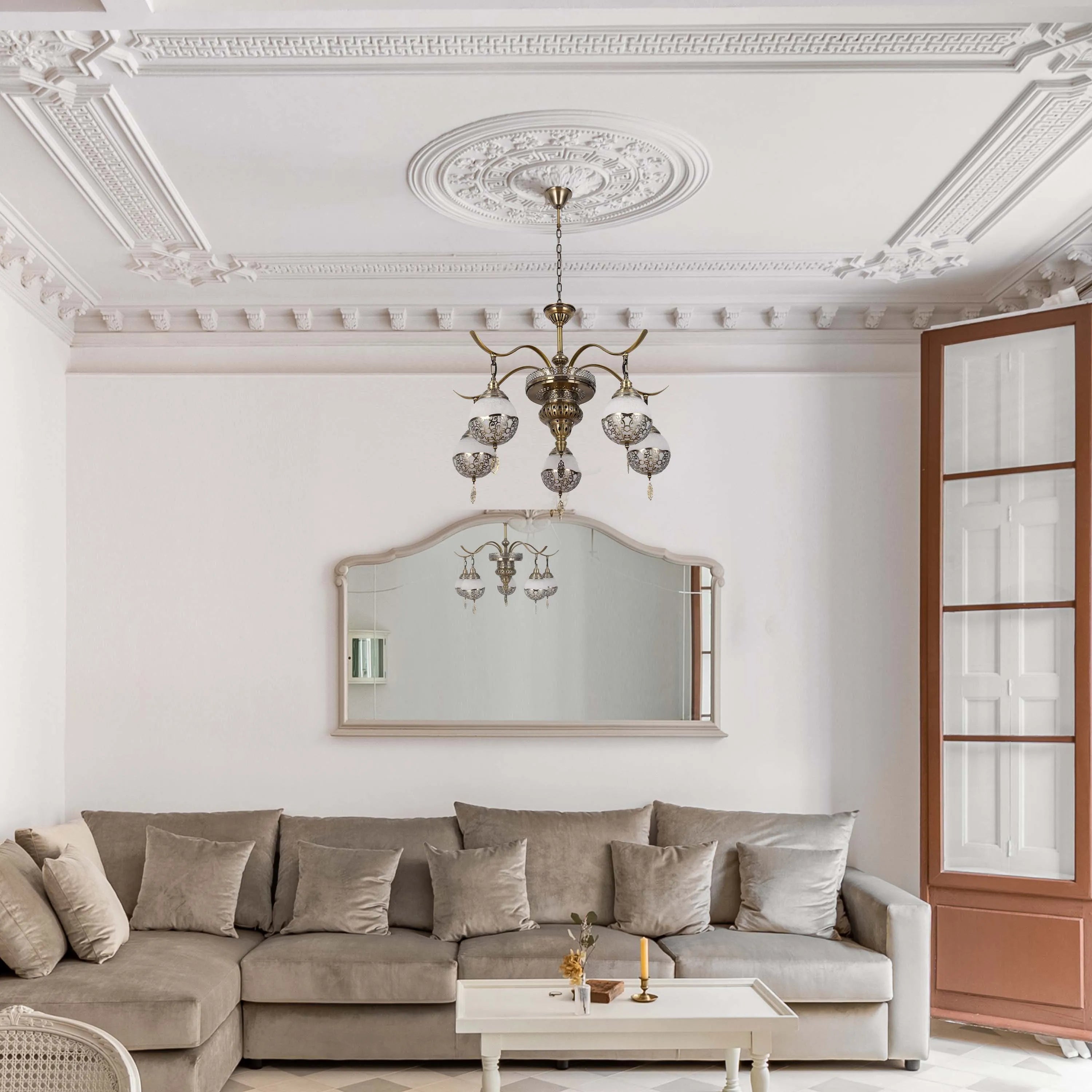 An ornate chandelier hangs from a decorative ceiling rose, providing ambient light to a sophisticated lounge setting.