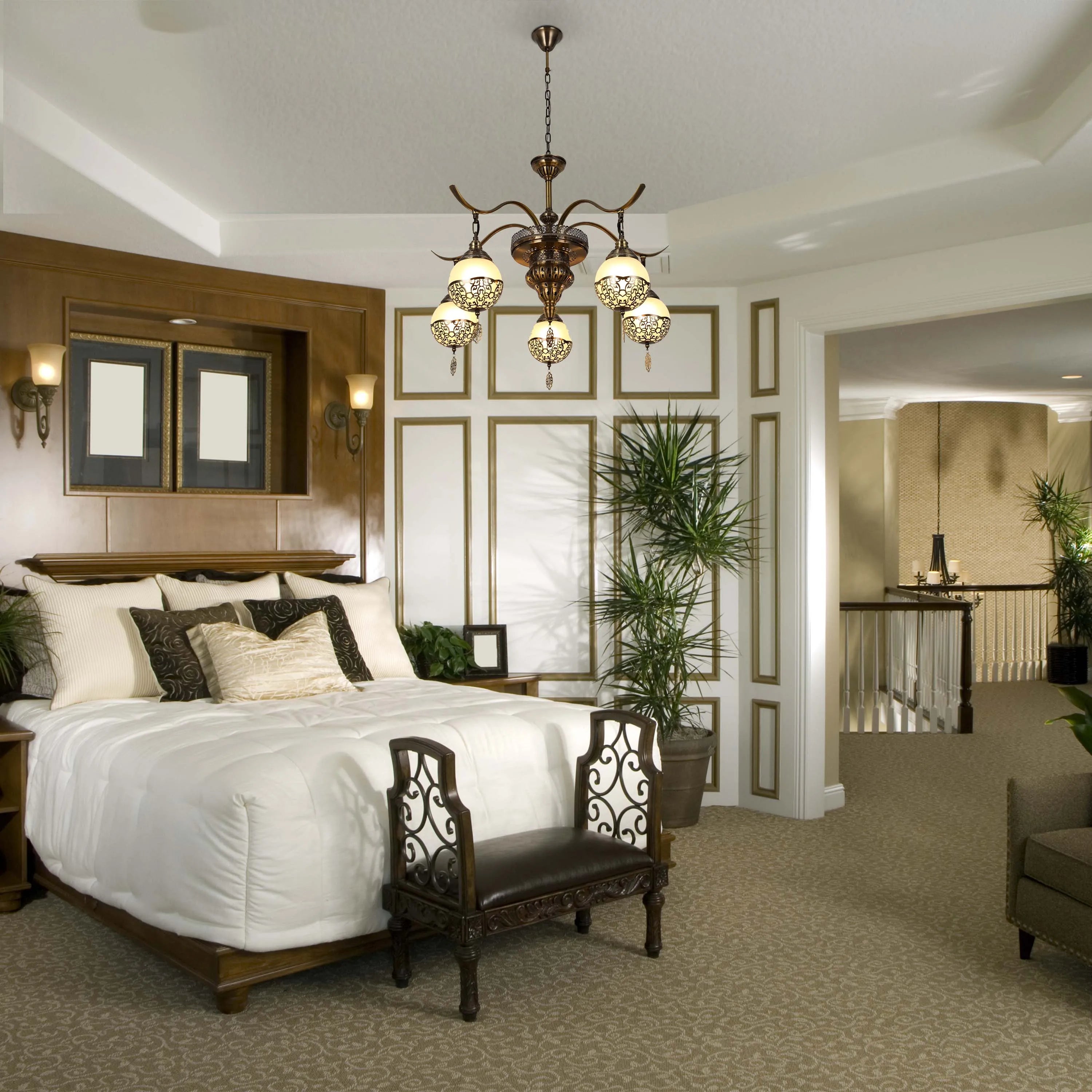 Ornate bedroom featuring a grand chandelier, wall-mounted lamps, and a glimpse of another chandelier down the hall.