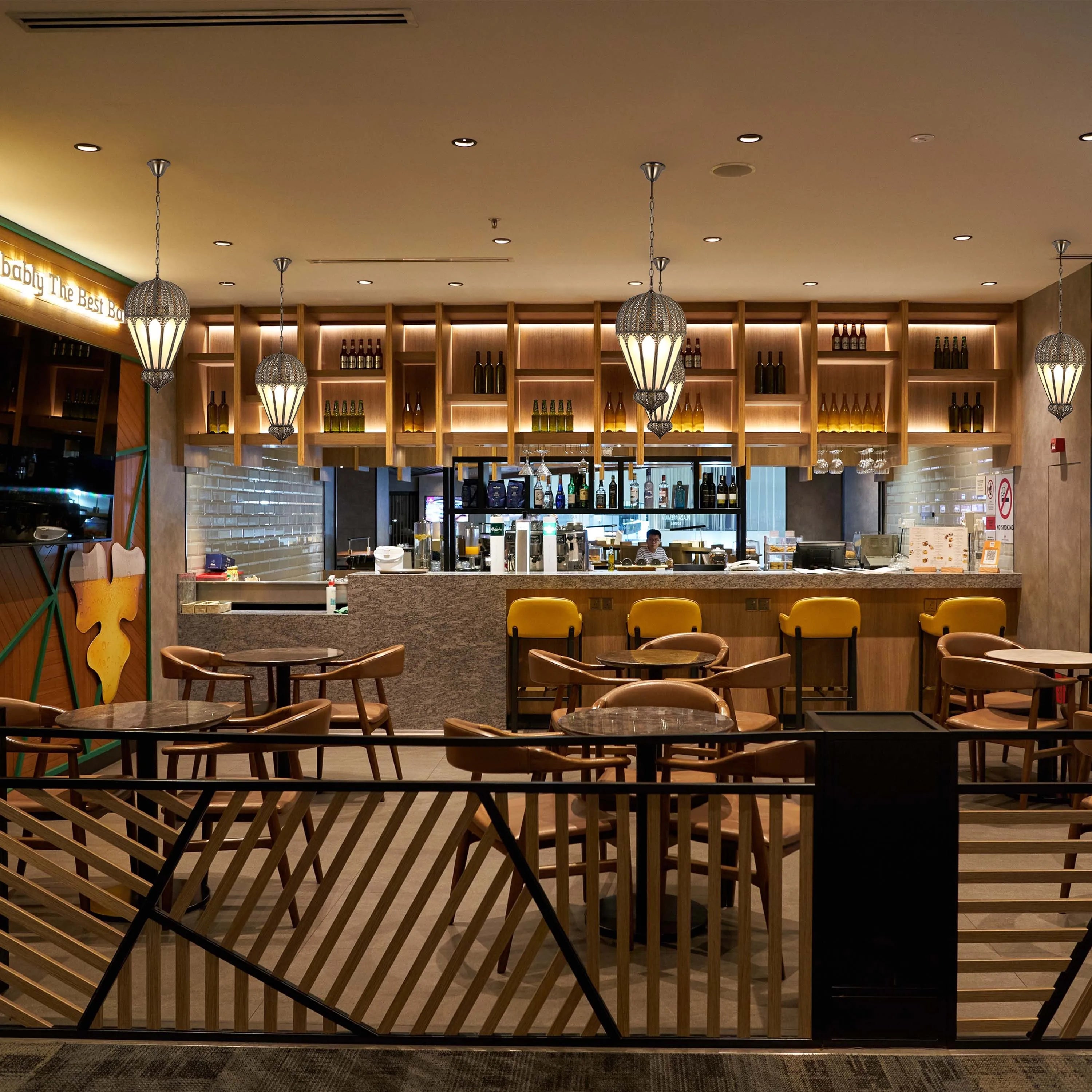 Contemporary lighting shines over a modern bar area with hanging lanterns and illuminated shelving. Warm, inviting ambience.