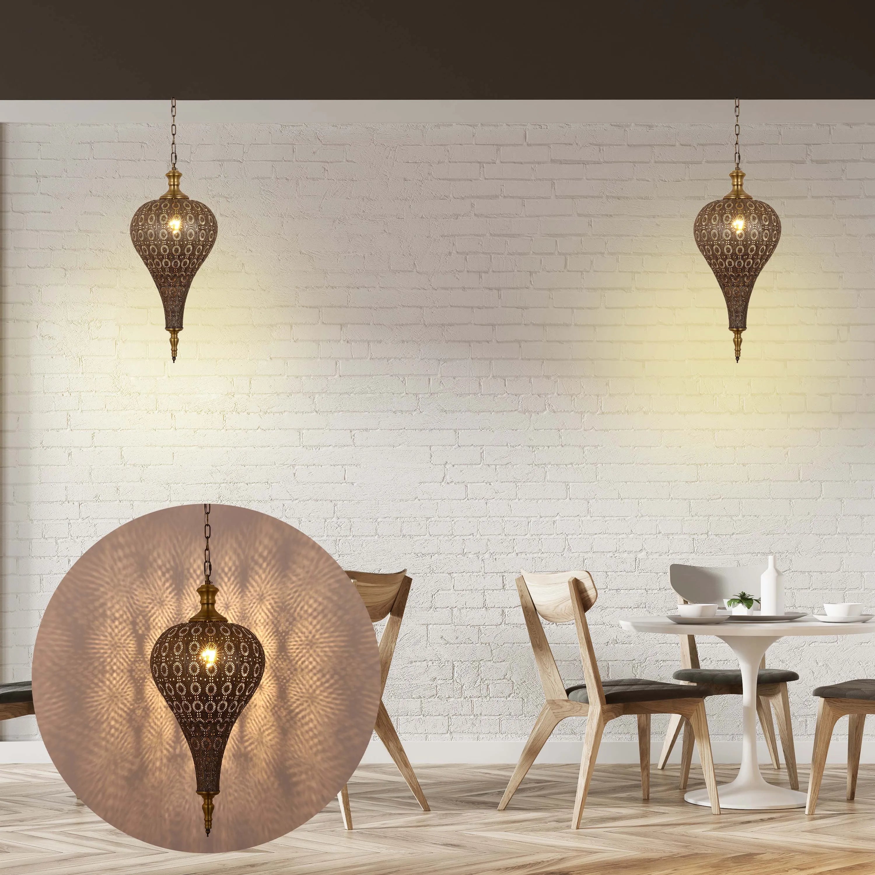 Two intricate gold pendant lights cast patterned shadows on a white brick wall in a dining area, creating a warm, inviting atmosphere.