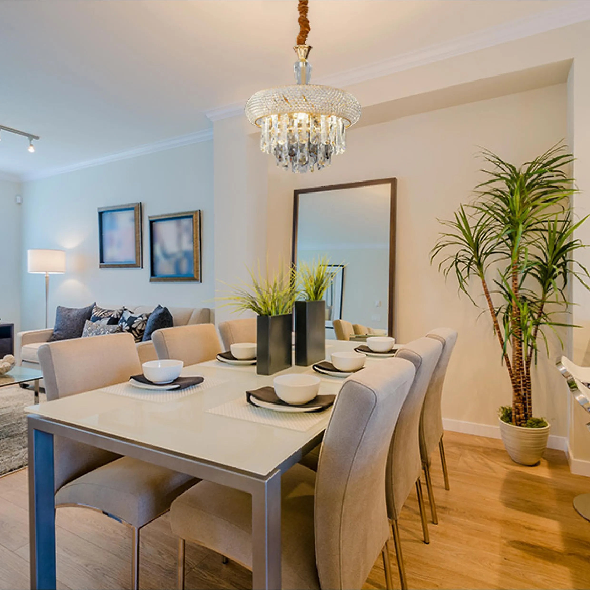 A glamorous chandelier hangs above a dining table, adding elegance with its cascading crystals and sparkling light in a modern interior.
