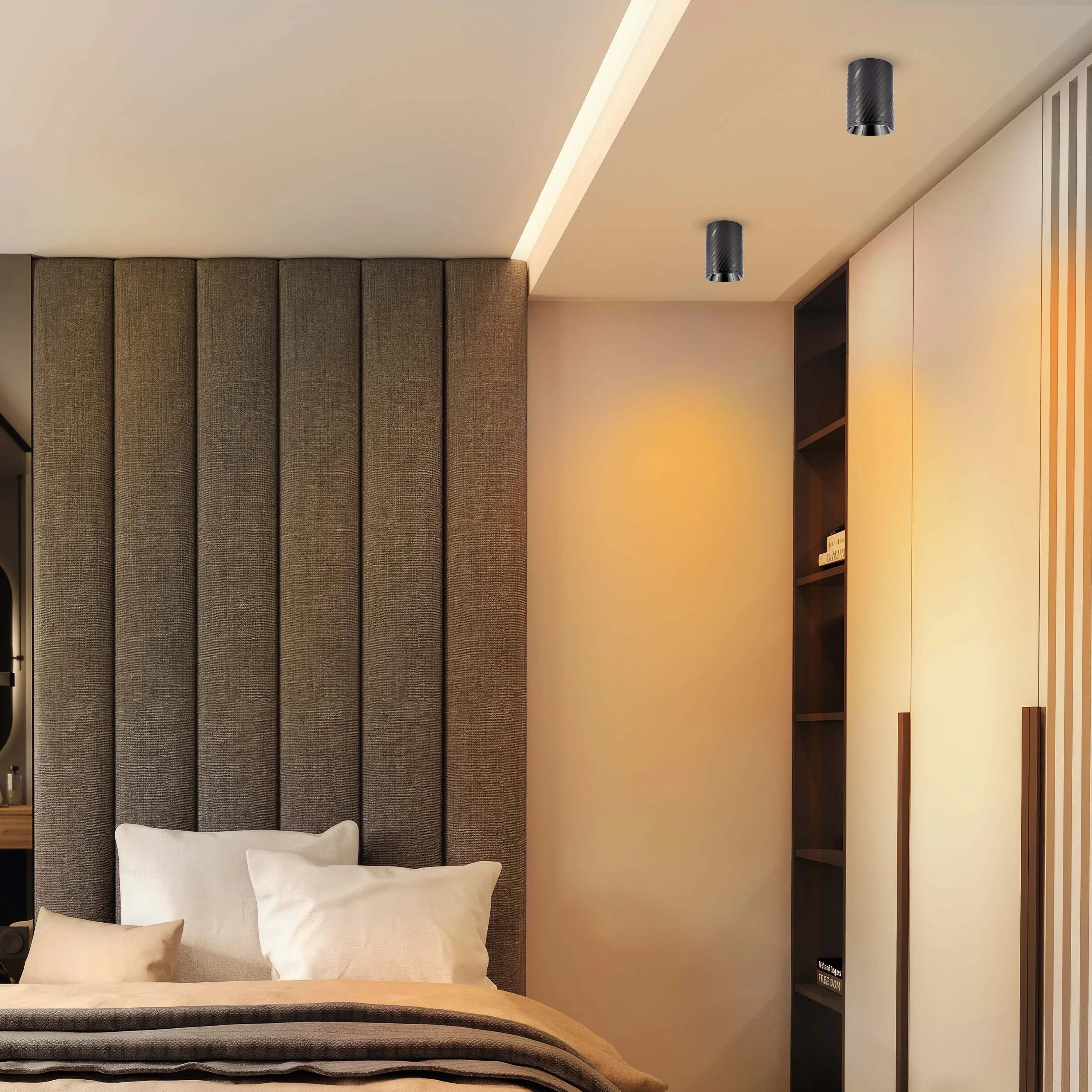 A bedroom with a bed and two overhead spotlights illuminating the ceiling. The wardrobe is also lit by an unseen light source.