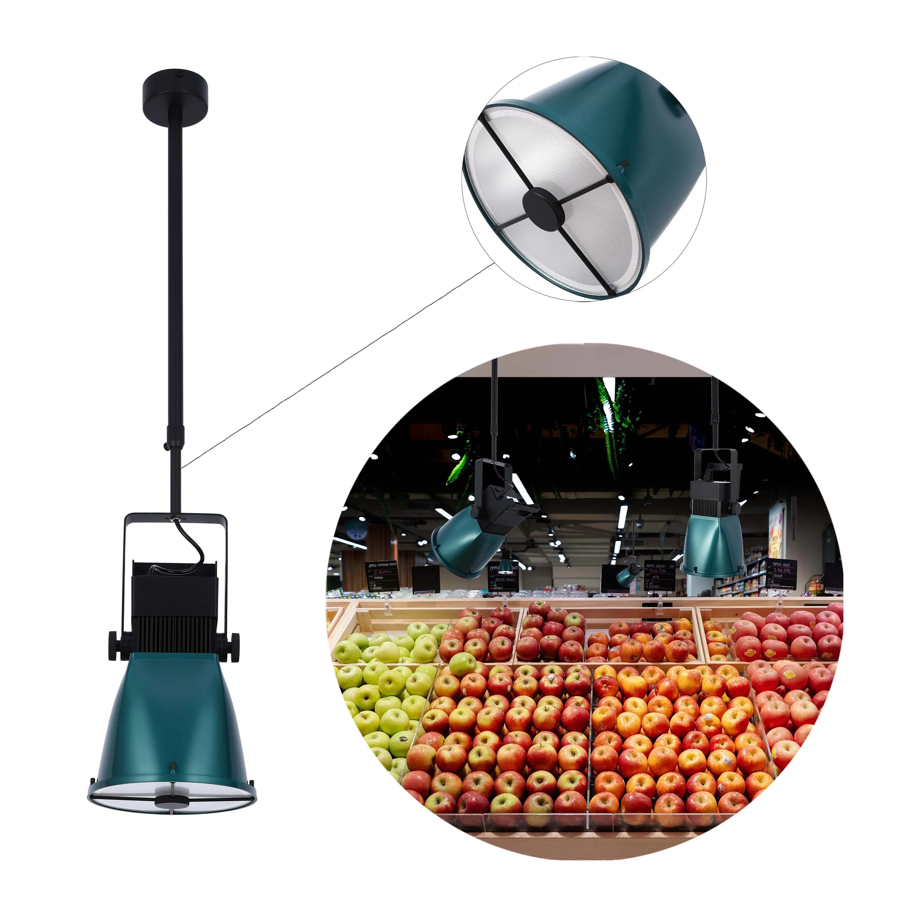 A green, industrial-style pendant light fixture illuminates fresh produce in a supermarket setting. Retro and functional design.