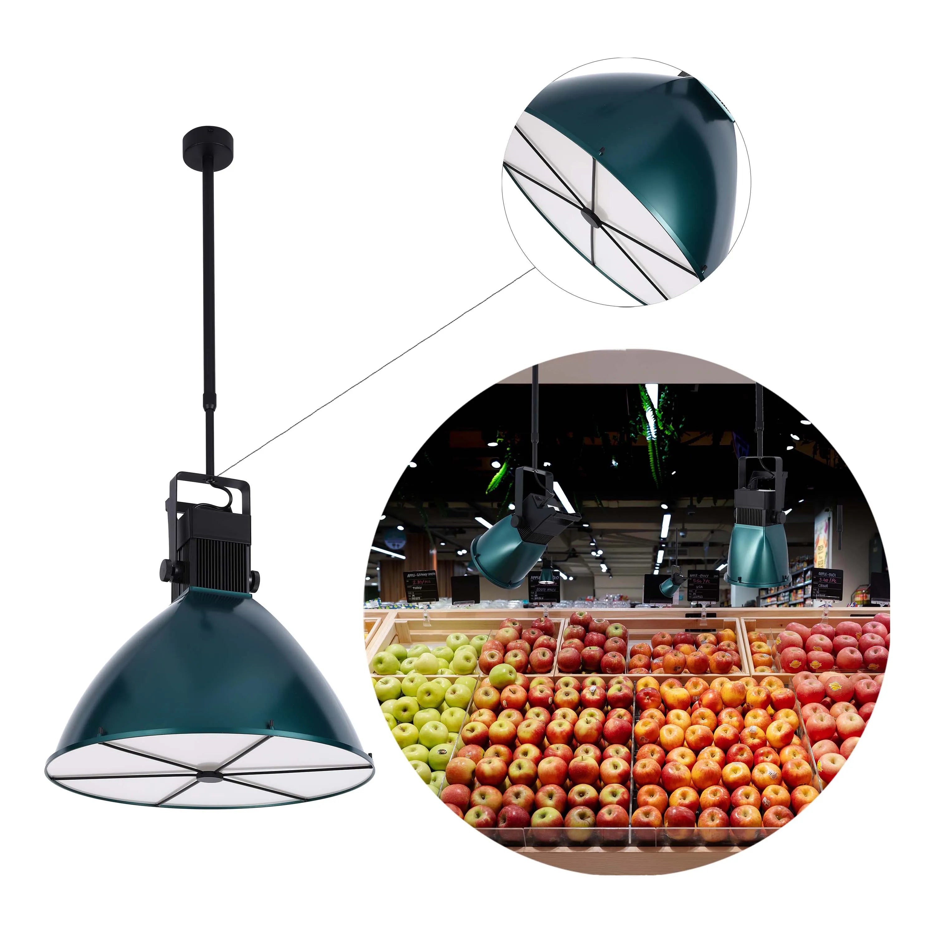 Modern green industrial pendant light and spotlights illuminate a colourful display of fresh apples in a supermarket.