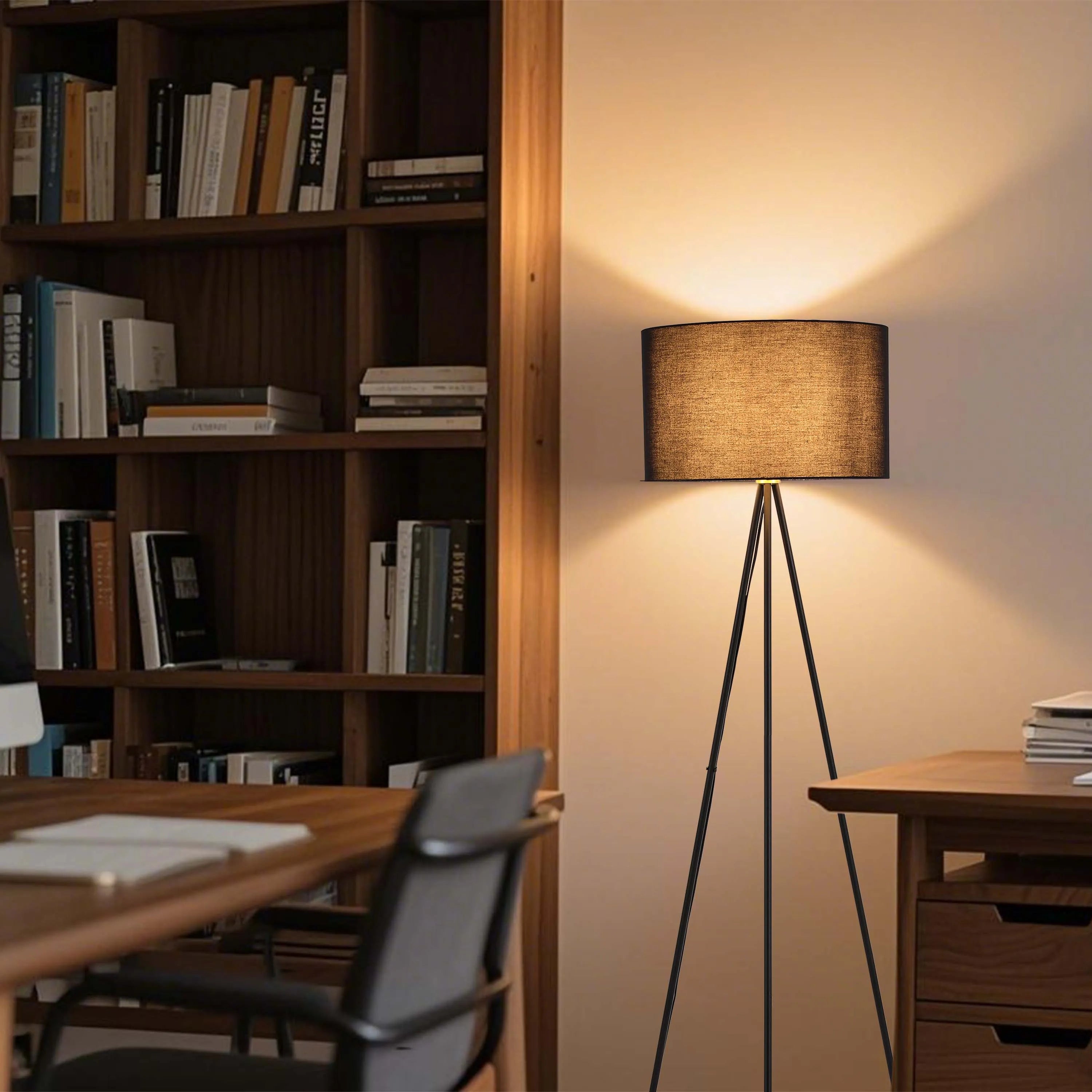A black tripod floor lamp with a warm shade casts a soft, inviting glow in a cosy living space, illuminating the room with elegance.