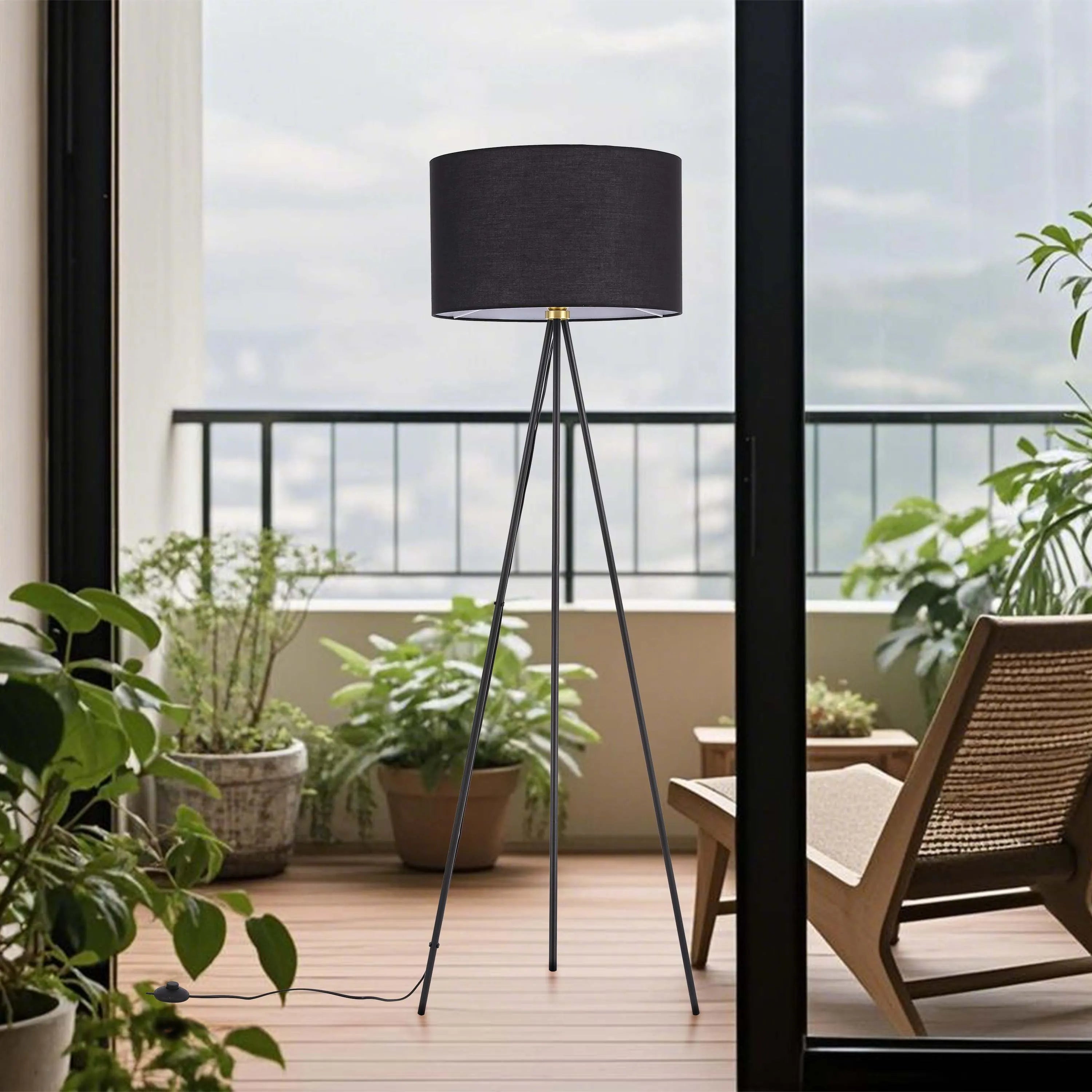 Black tripod floor lamp with a fabric shade, illuminating a bright, modern balcony.