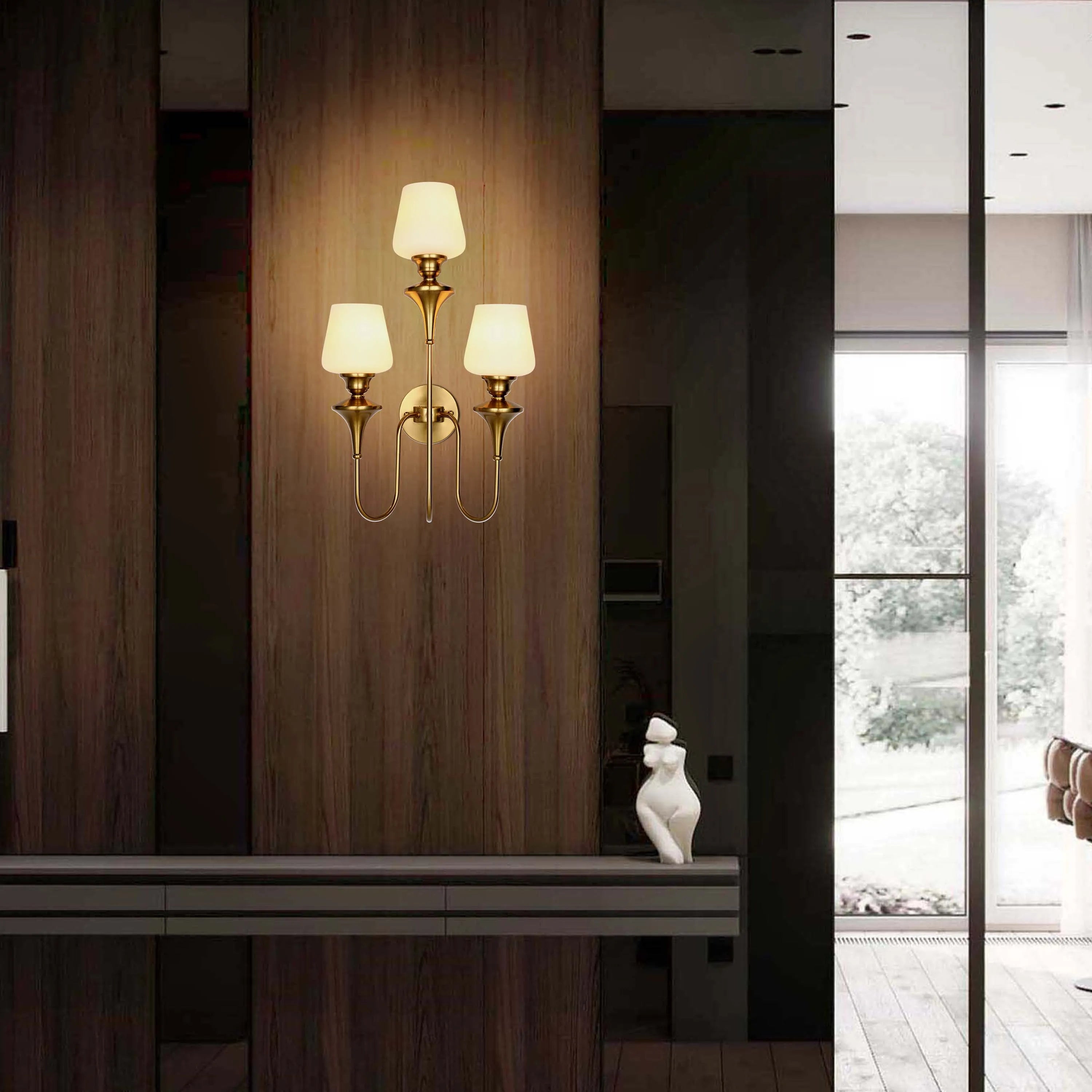 Wall-mounted light fixture with three lights in a vertical arrangement. It has brass arms and white lampshades.