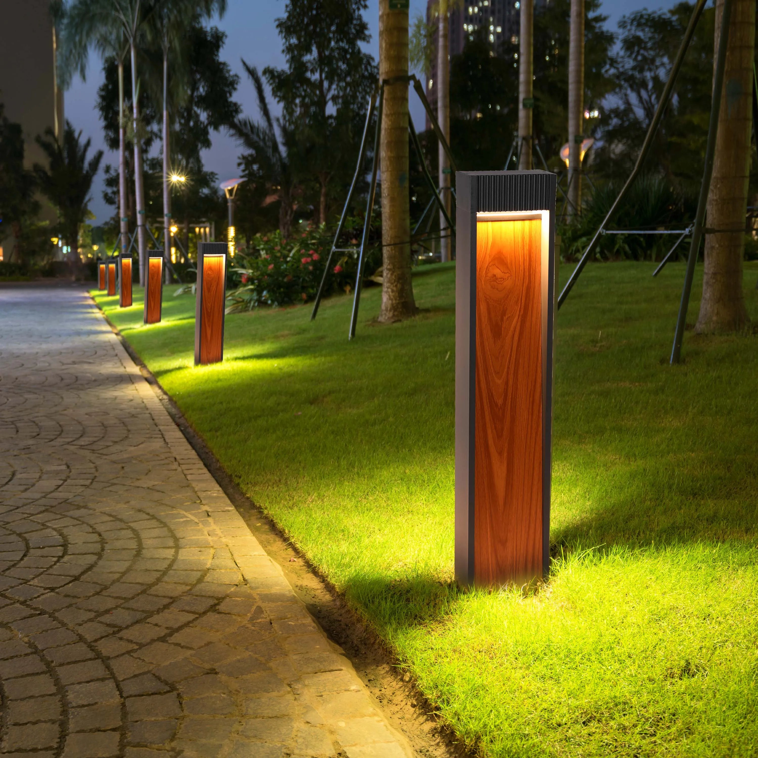 Modern bollard lights illuminate a paved walkway and lawn at night, creating a warm and inviting ambience.